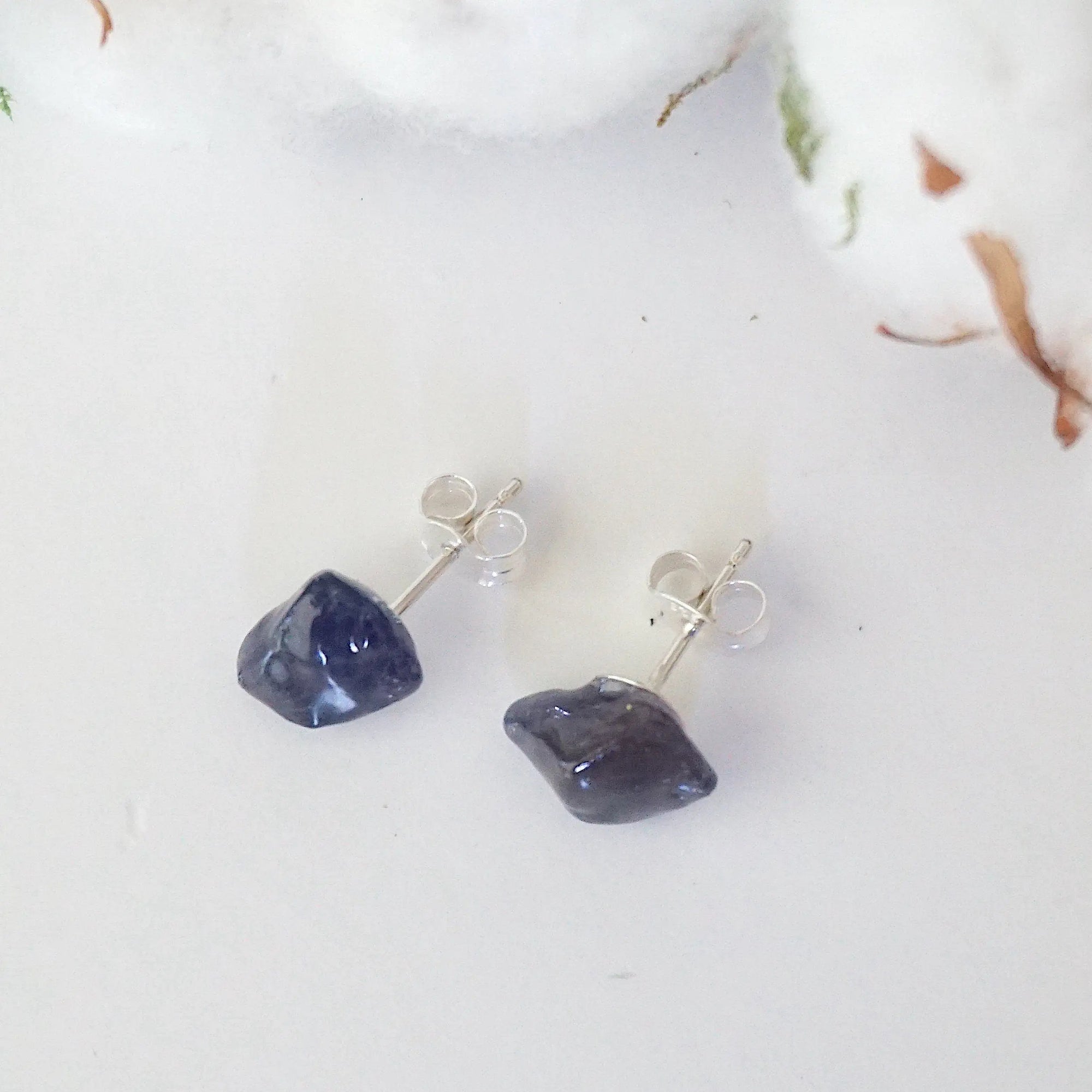 Top-angle view of raw sapphire stud earrings showing the natural blue stones and minimalist sterling silver design