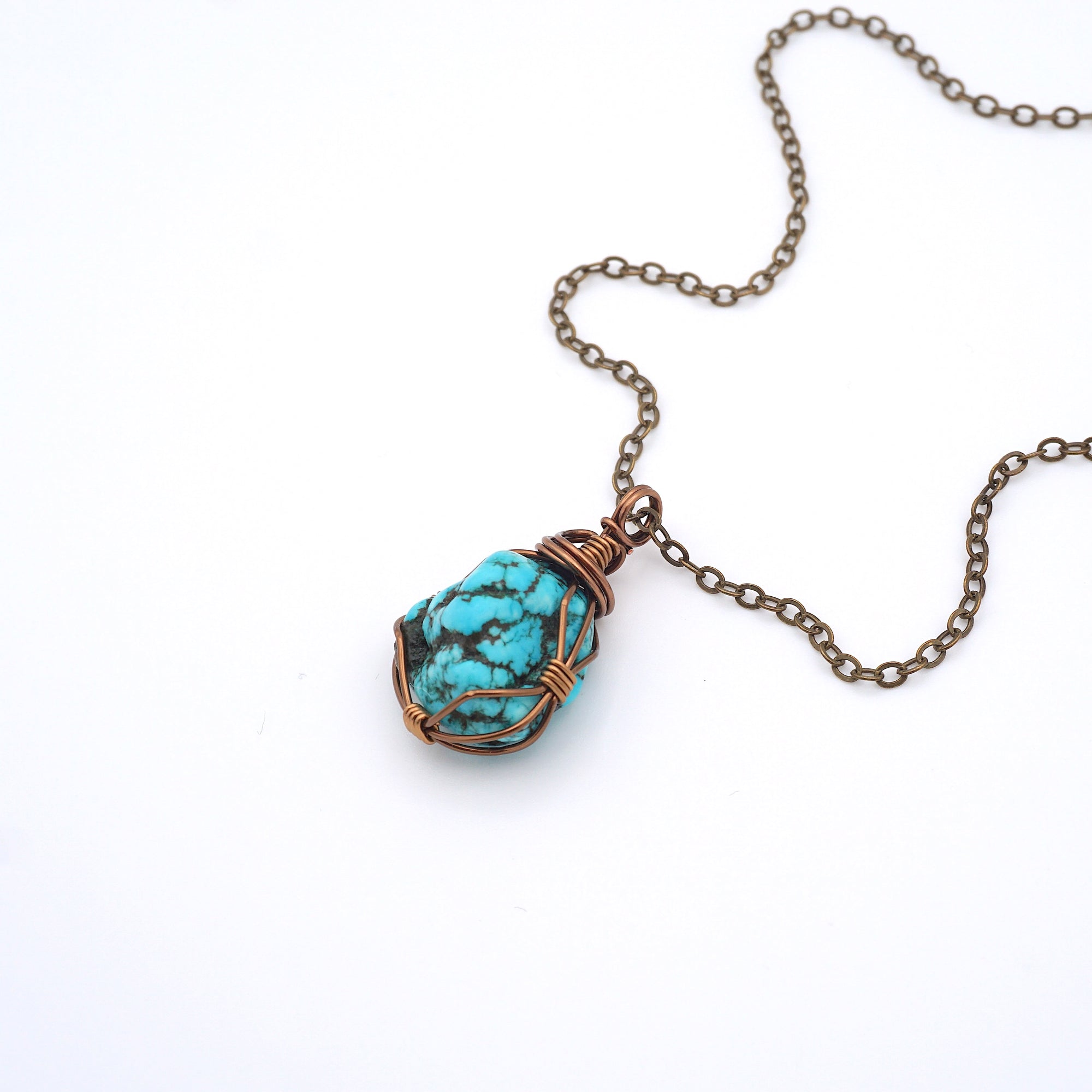 Raw turquoise necklace with antique bronze copper wire wrapping on chain, handmade crystal healing pendant flat lay