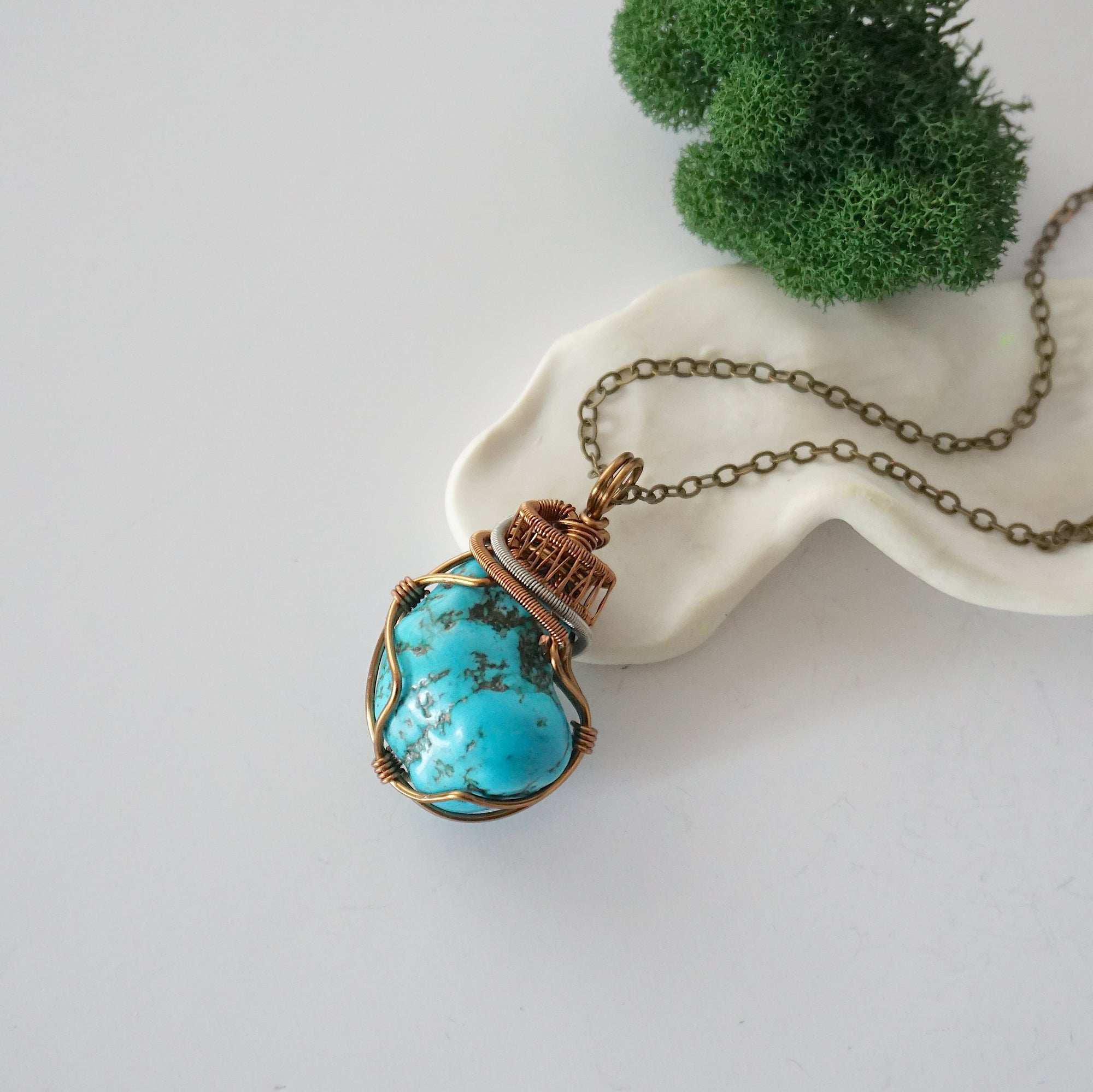 Raw turquoise necklace with detailed antique bronze copper wire wrapping on chain, handmade crystal pendant flat lay