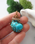 Raw turquoise pendant in hand showing size, detailed wire wrapped crystal necklace with copper accents scale reference