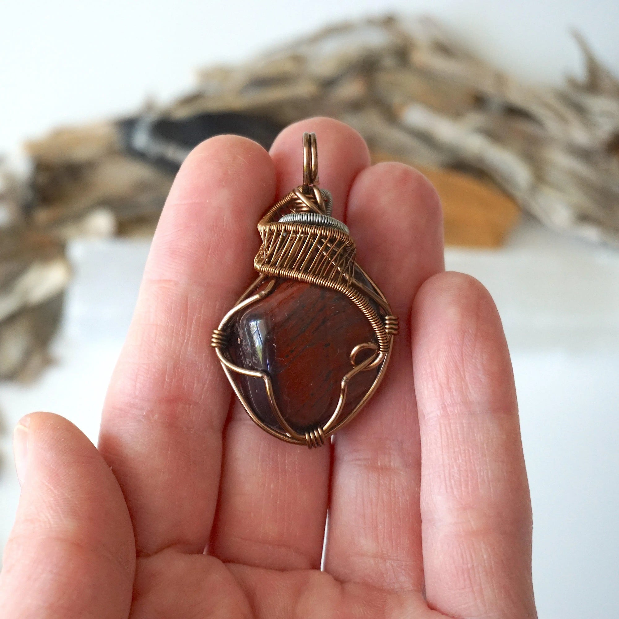 Natural red tiger's eye pendant in hand for size reference, handcrafted by Designs by Nature Gems.