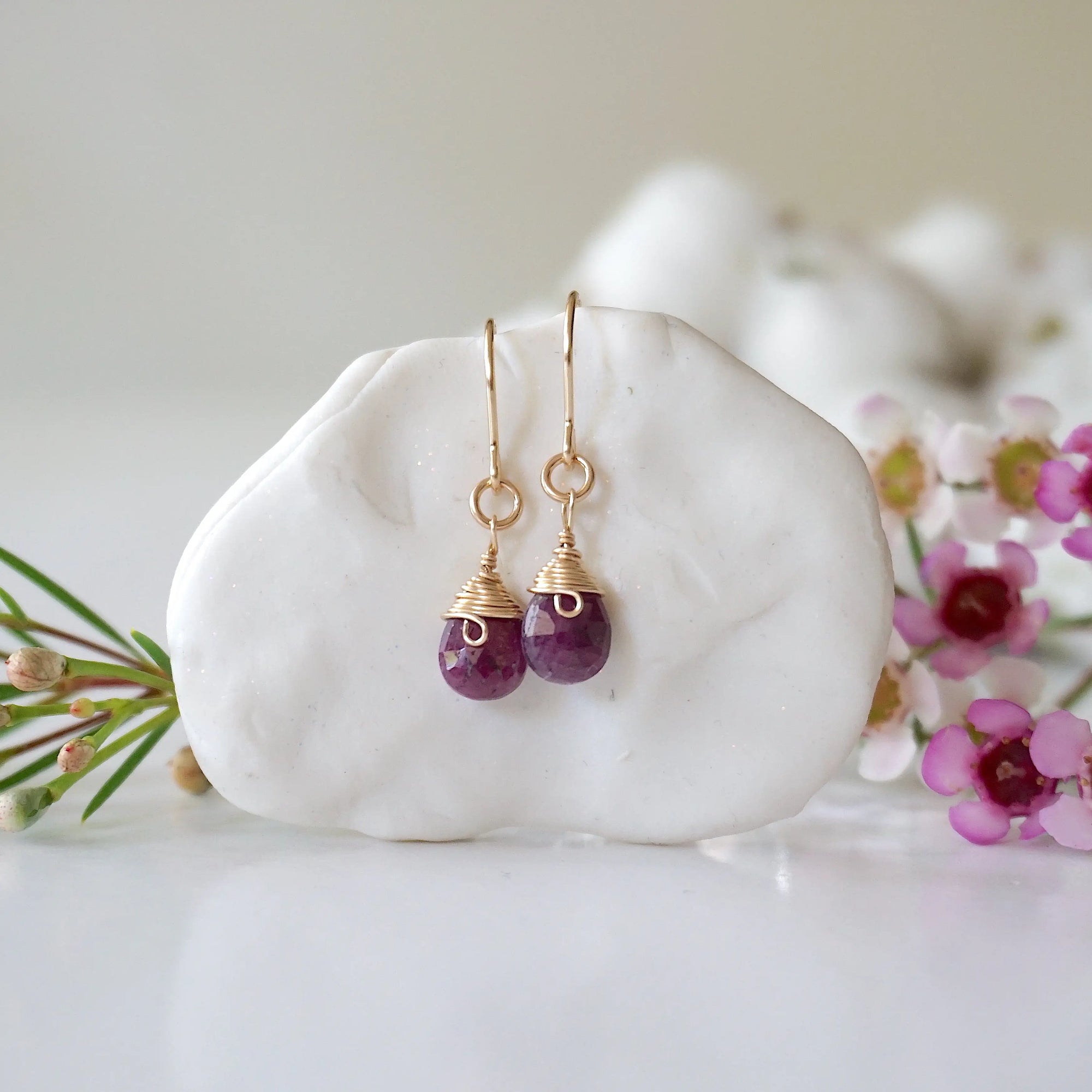 Detailed front view of ruby drop earrings, genuine faceted ruby with minimalist 14k gold filled wire wrapping, Designs by Nature Gems