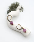 Bird’s eye view of ruby drop earrings laying flat on a display, showing detailed wire wrapping and gemstone color.