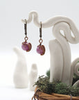 Front angle of ruby drop earrings hanging on a jewelry display, wire-wrapped design.