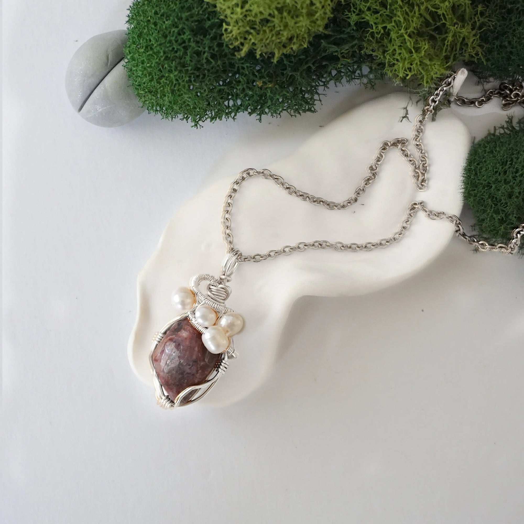 Handmade silver wire wrapped ruby and freshwater pearl necklace laying flat on a silver plated chain, artisan jewelry for women