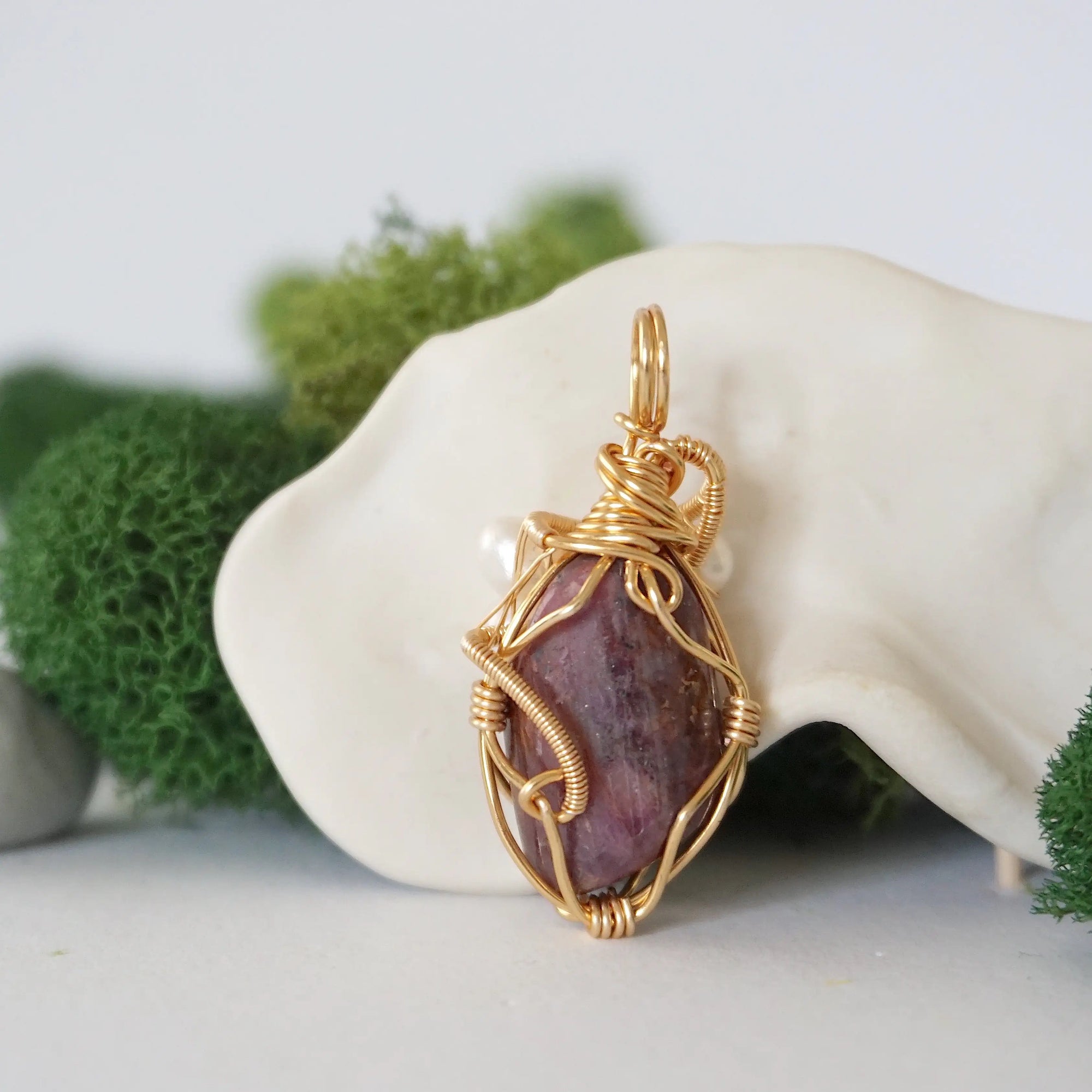 Back angle detail of ruby and freshwater pearl pendant, showing wire wrapping and natural stone