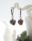 Close-up of handcrafted sapphire drop earrings with antique bronze copper wire wrapping.