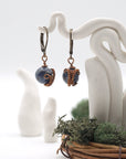 Front angle of sapphire drop earrings hanging on a jewelry display, wire-wrapped design.