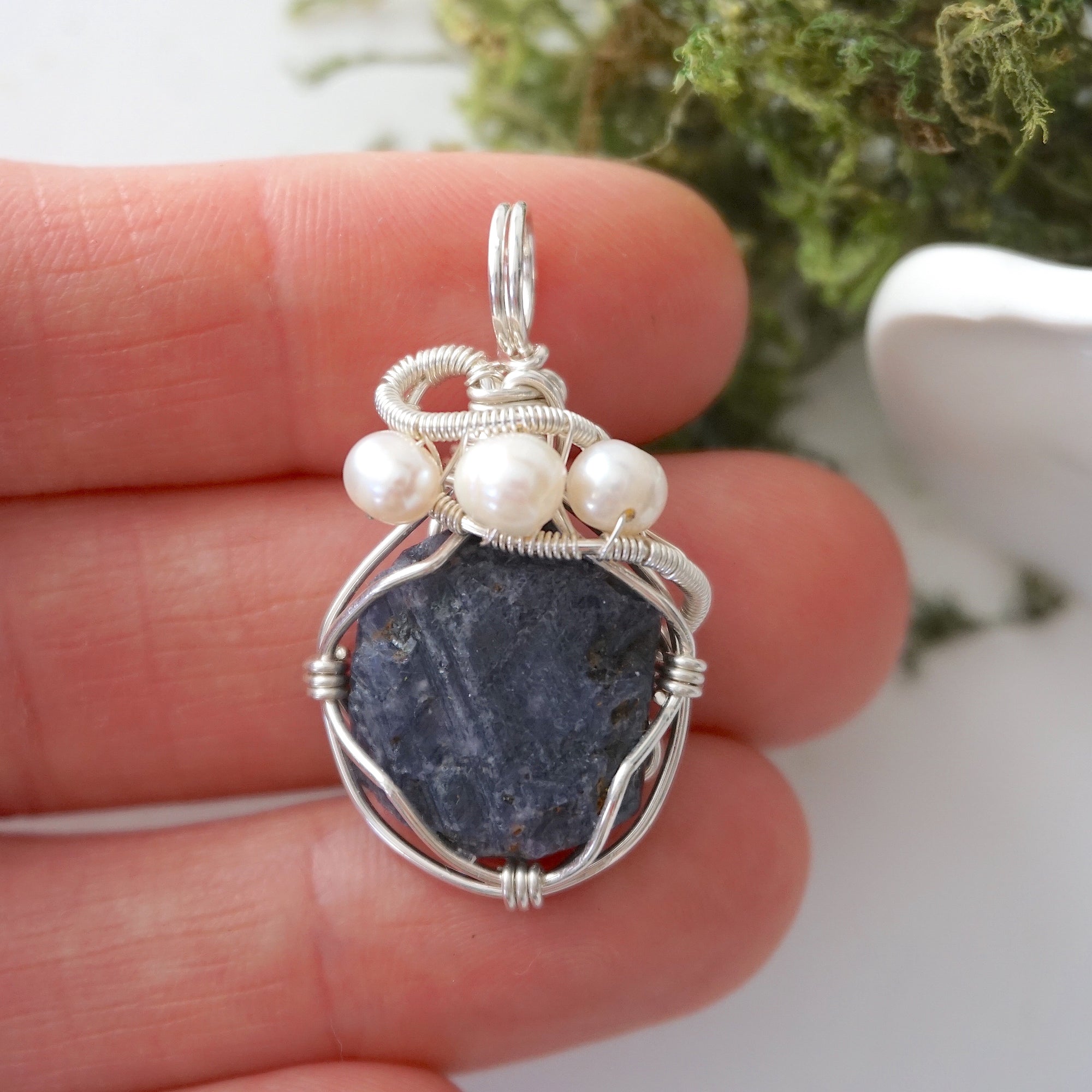 Sapphire and freshwater pearl pendant necklace in hand for size reference, silver wire wrapped, handcrafted gemstone jewelry