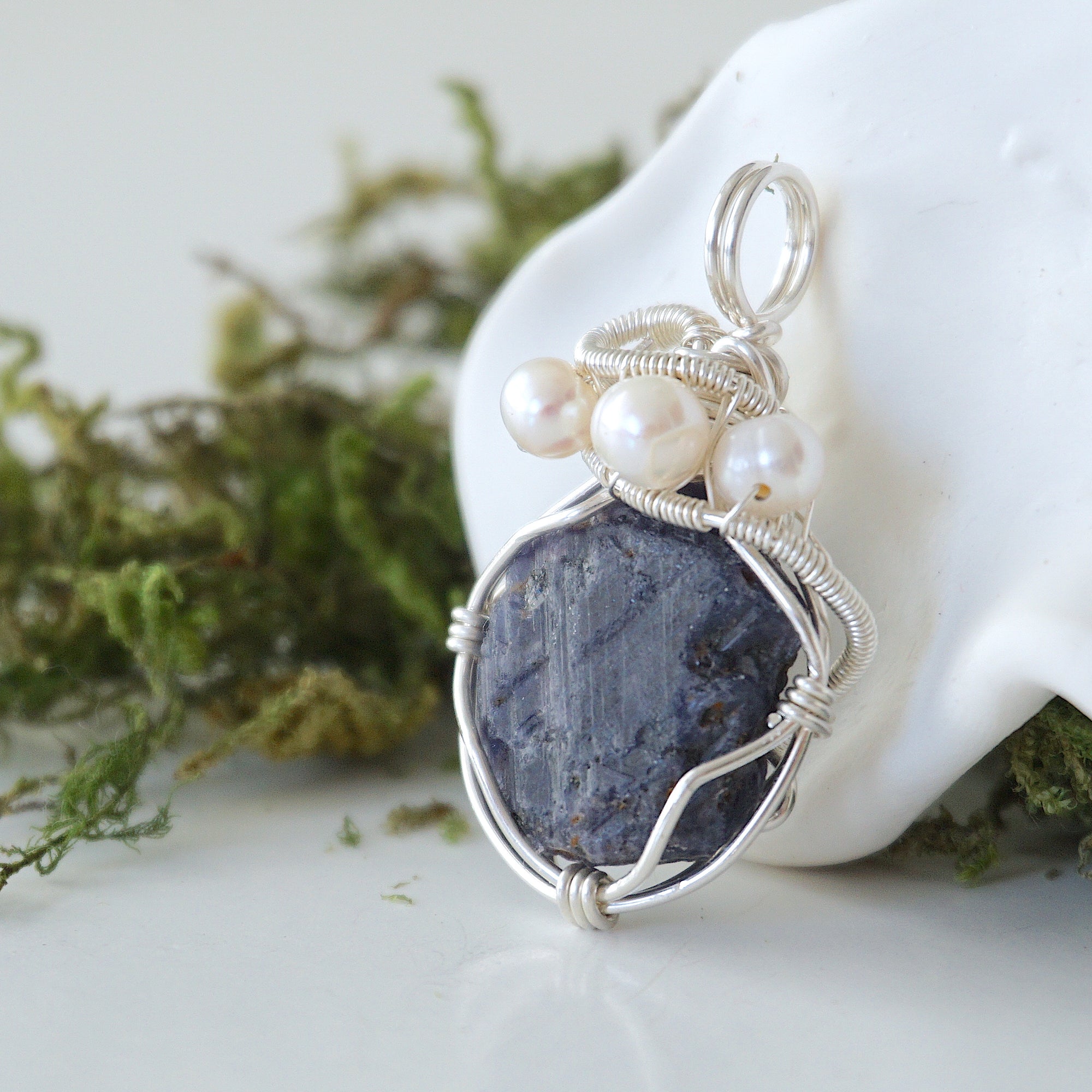 Side angle of handmade sapphire and freshwater pearl pendant necklace, silver wire wrapped jewelry