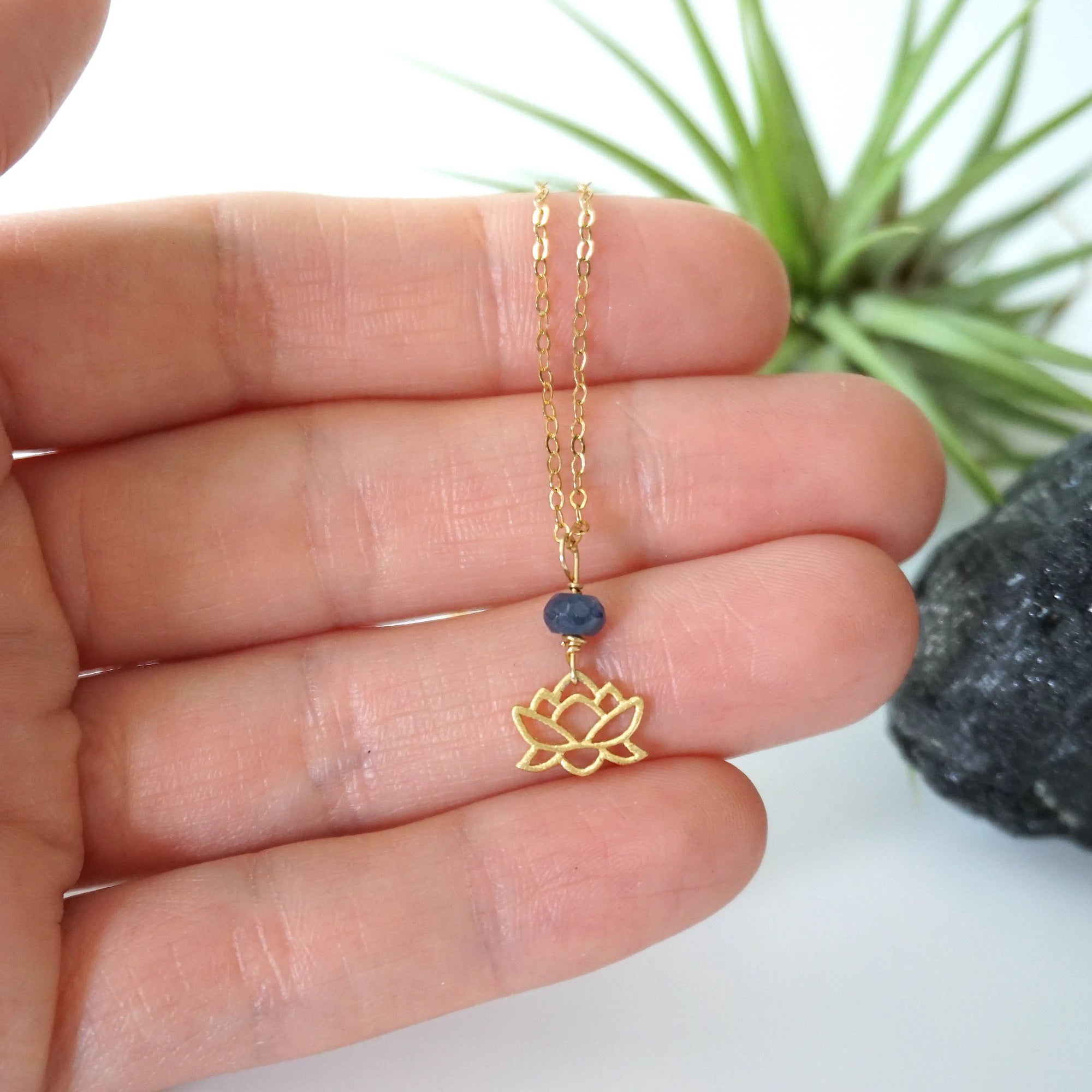 Sapphire and gold vermeil lotus necklace held in hand to show size — minimalist September birthstone jewelry handcrafted in Toronto
