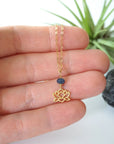 Sapphire and gold vermeil lotus necklace held in hand to show size — minimalist September birthstone jewelry handcrafted in Toronto