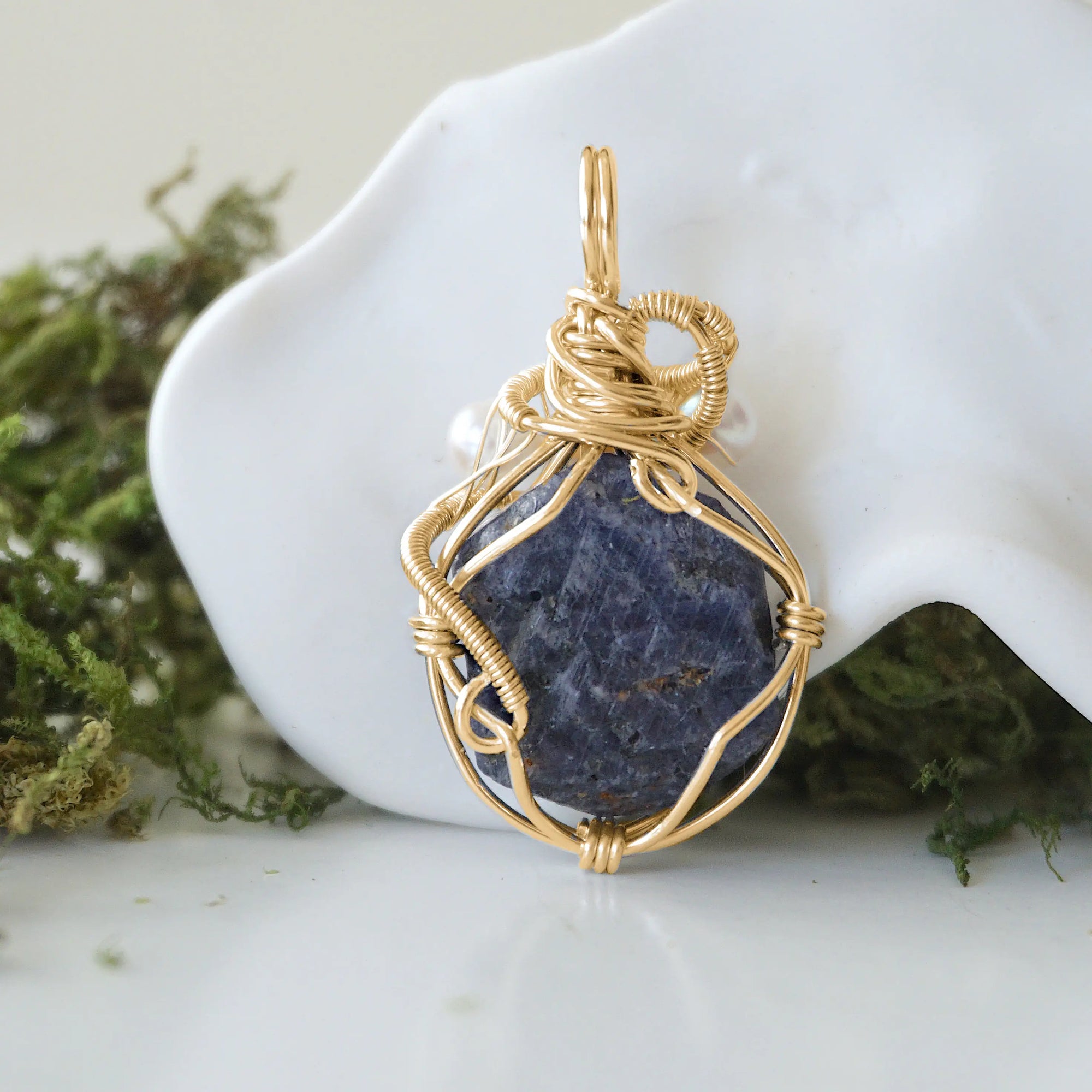 Back angle detail of sapphire and freshwater pearl pendant, showing wire wrapping and natural stone