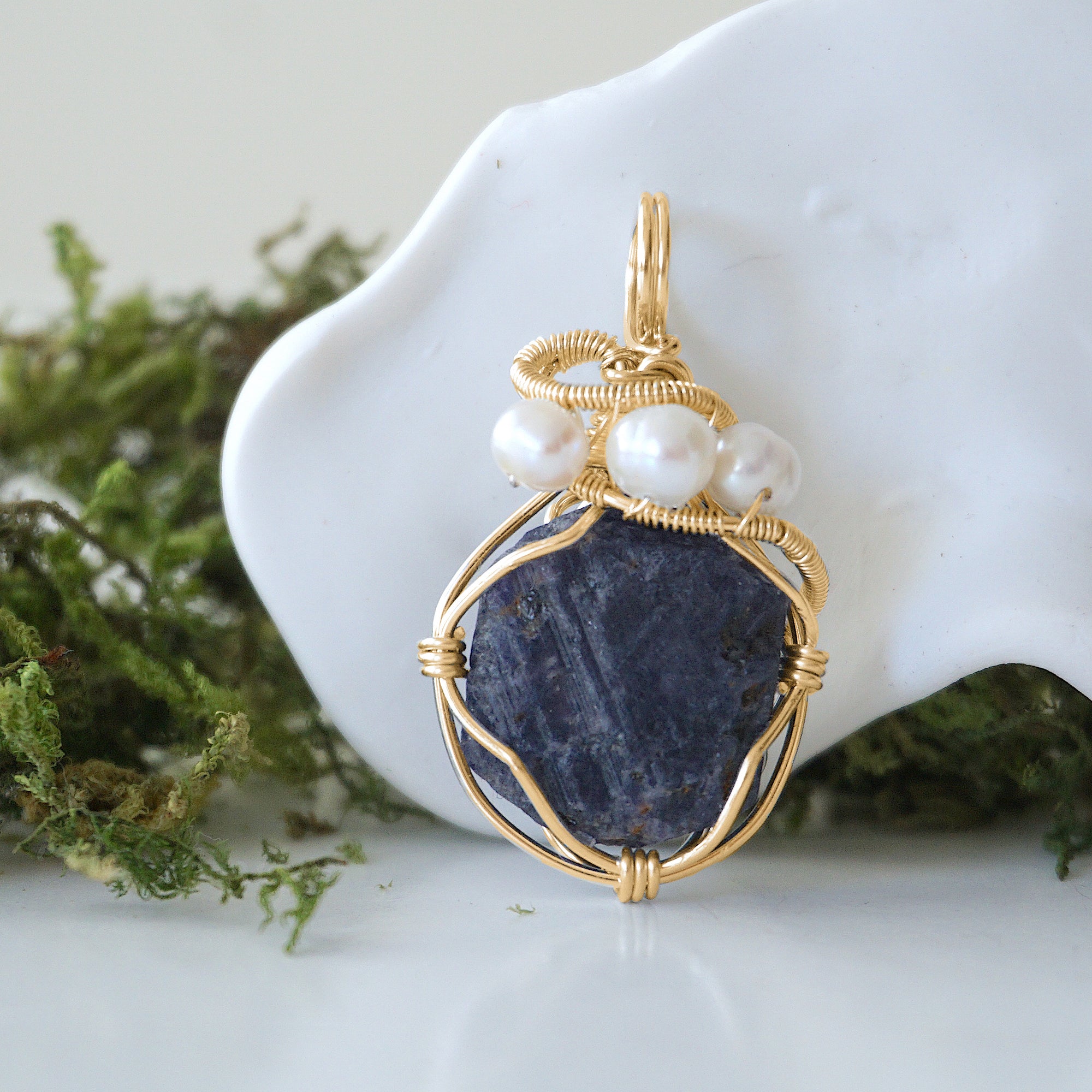 Detailed front angle of sapphire and freshwater pearl pendant, gold wire wrapped, handcrafted gemstone jewelry