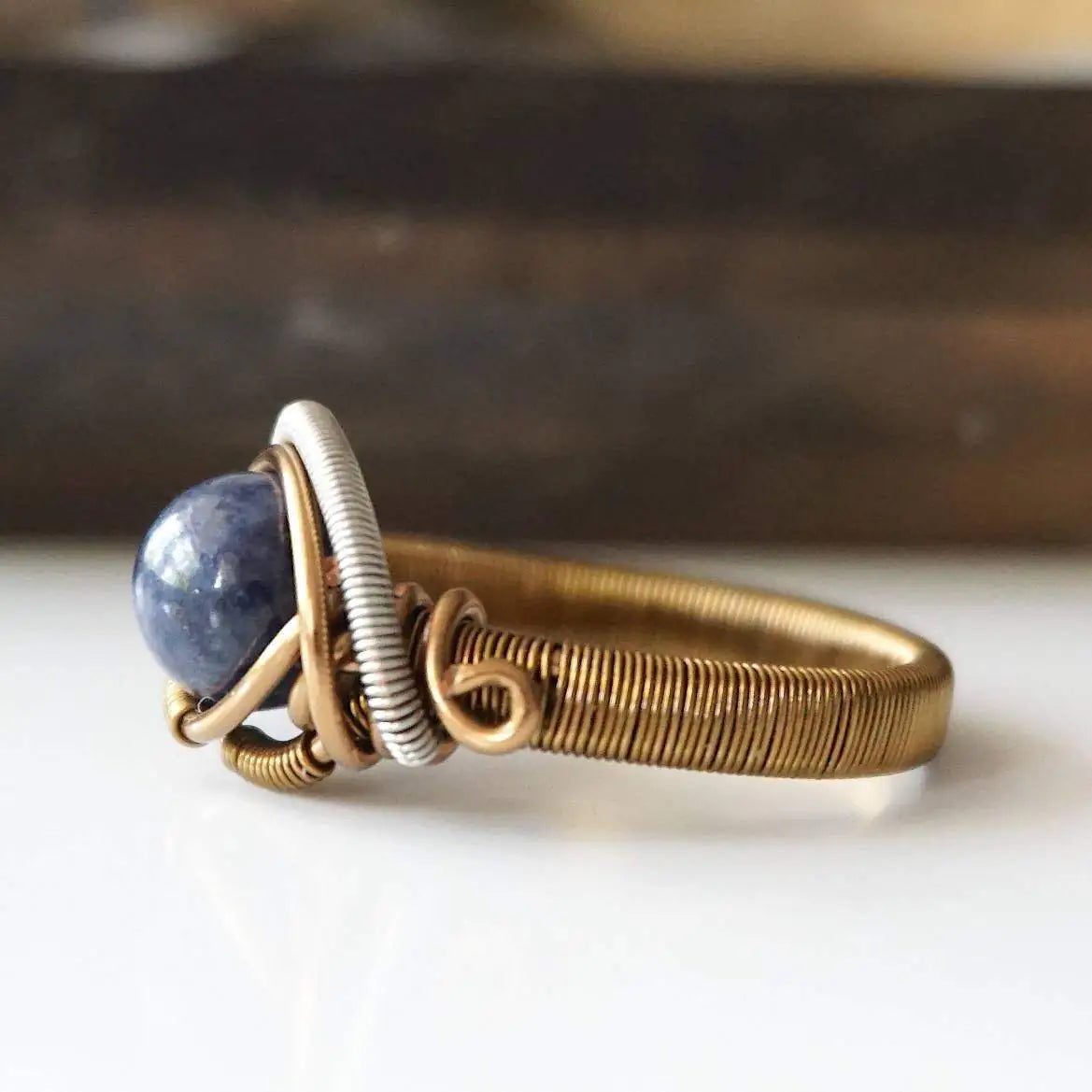 Side-angle detail of natural sapphire ring showing the artisan wire wrapping in antique bronze and dark silver finish