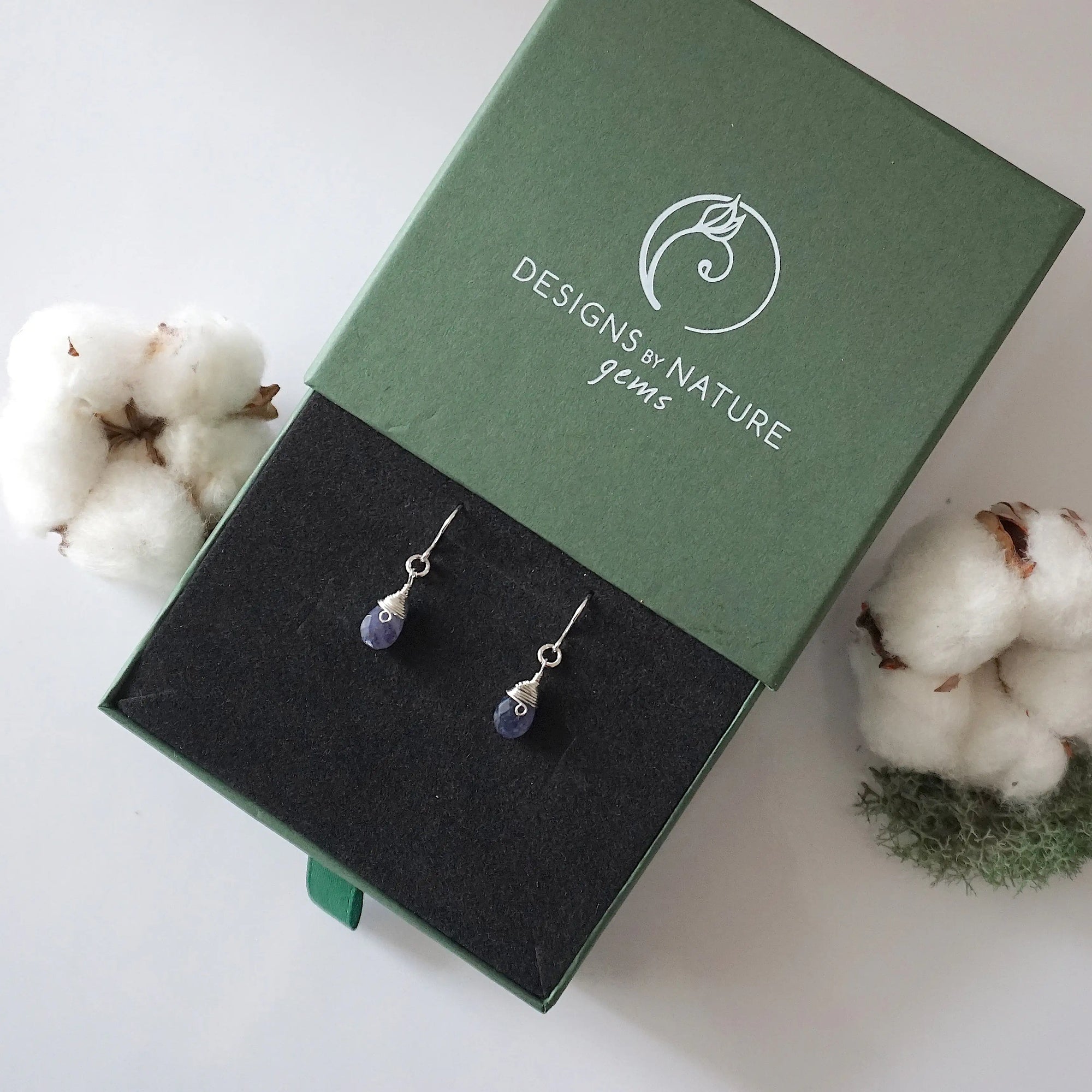 Sapphire sterling silver drop earrings in branded Designs by Nature Gems jewelry box, showcasing handcrafted faceted sapphire and sterling silver wire wrapping