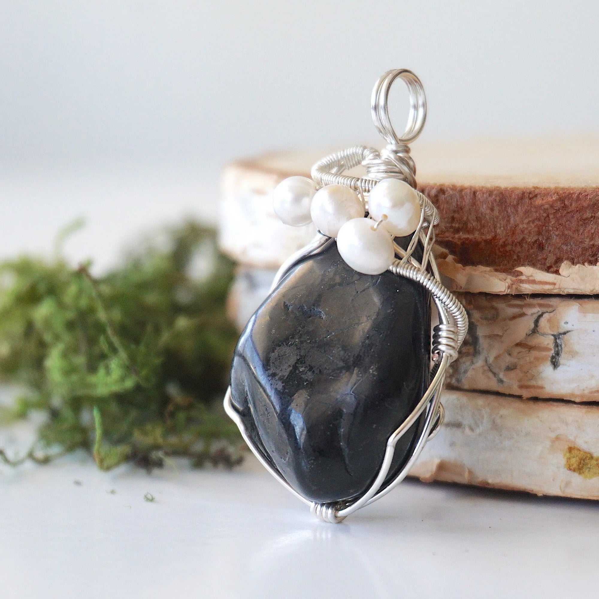 Side angle of handmade shungite and freshwater pearl pendant necklace, silver wire wrapped jewelry
