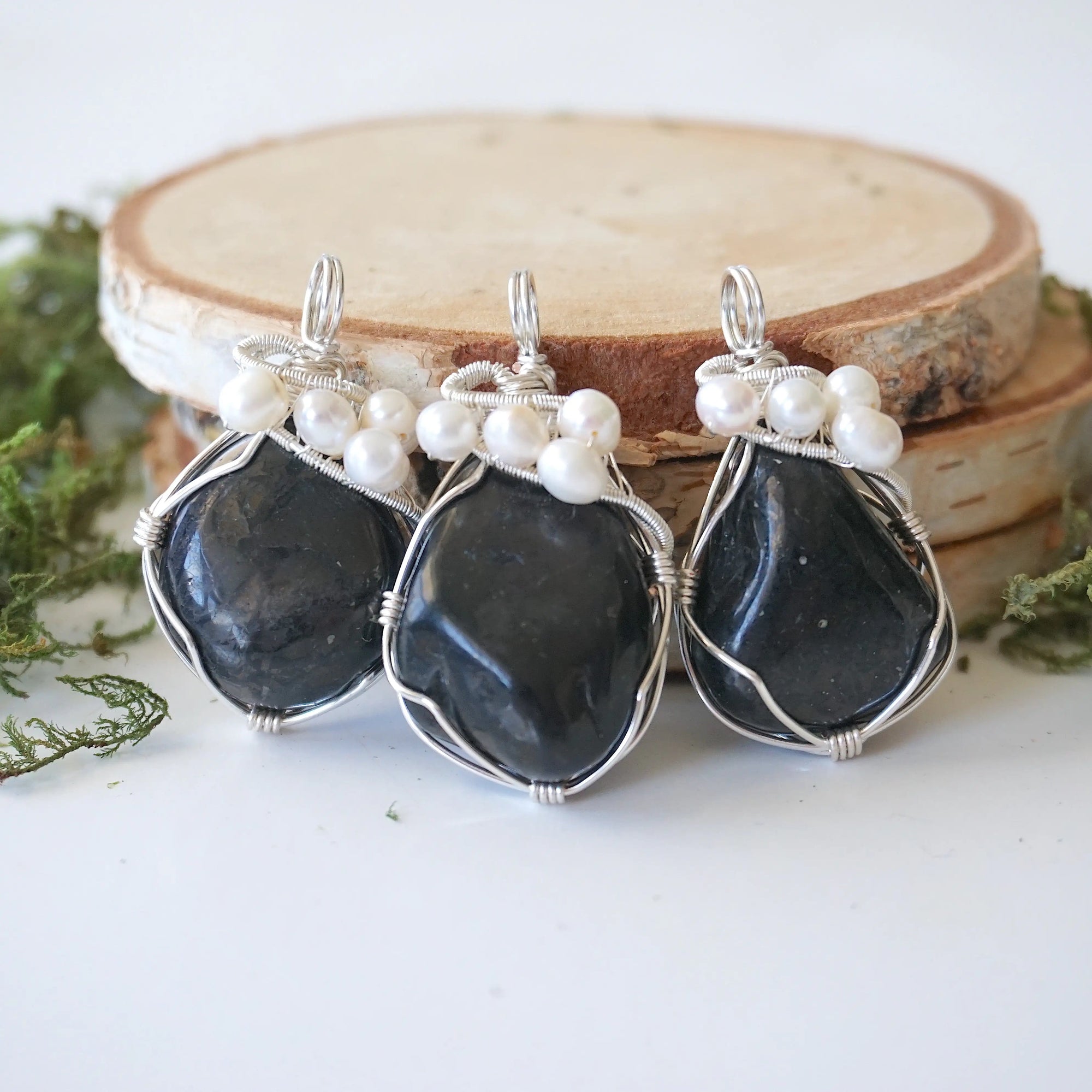 Three silver wire wrapped shungite and freshwater pearl pendants showing natural stone variation, artisan jewelry for women