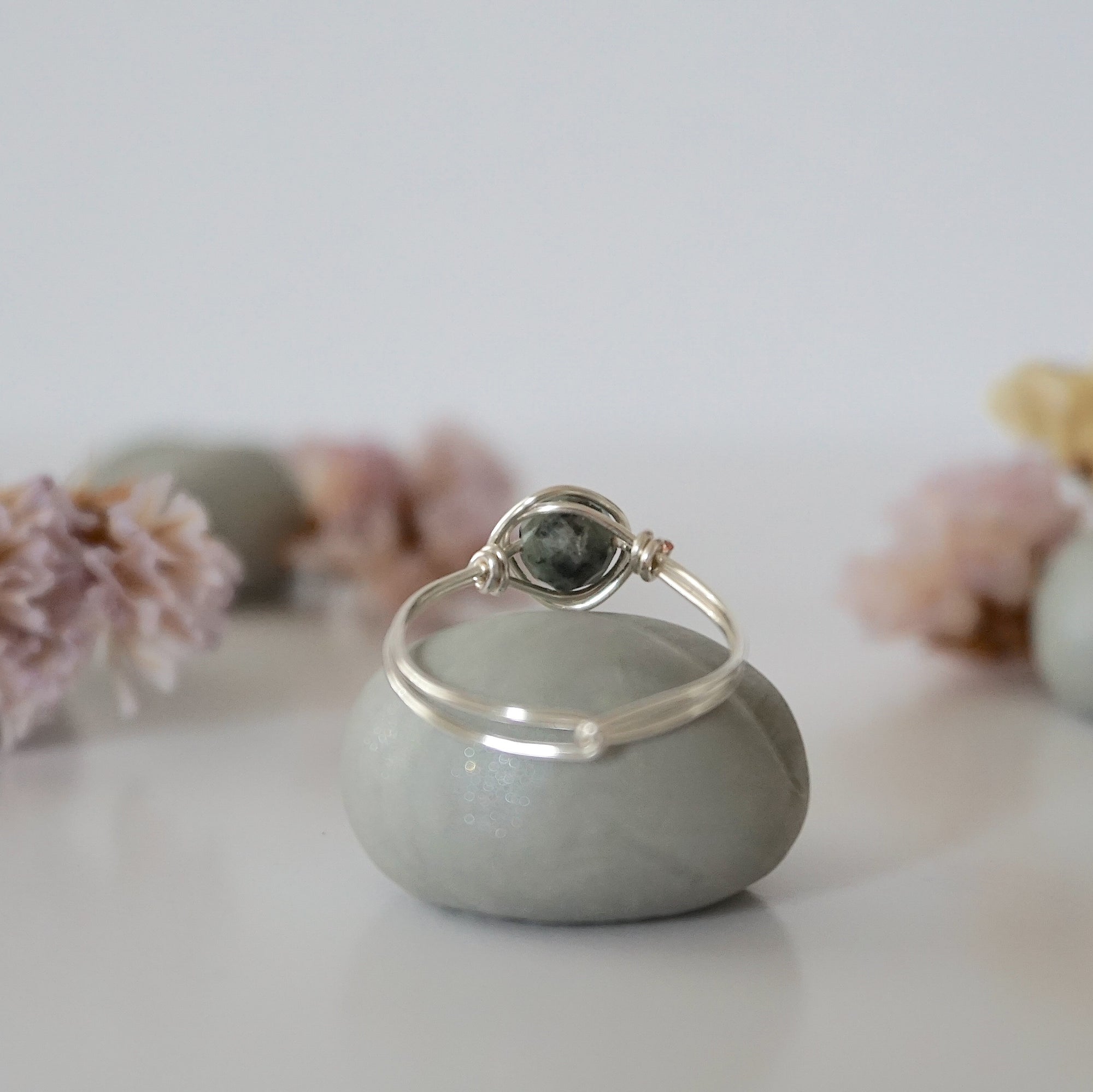 Back view of minimalist silver emerald ring highlighting handcrafted wire wrapping detail.