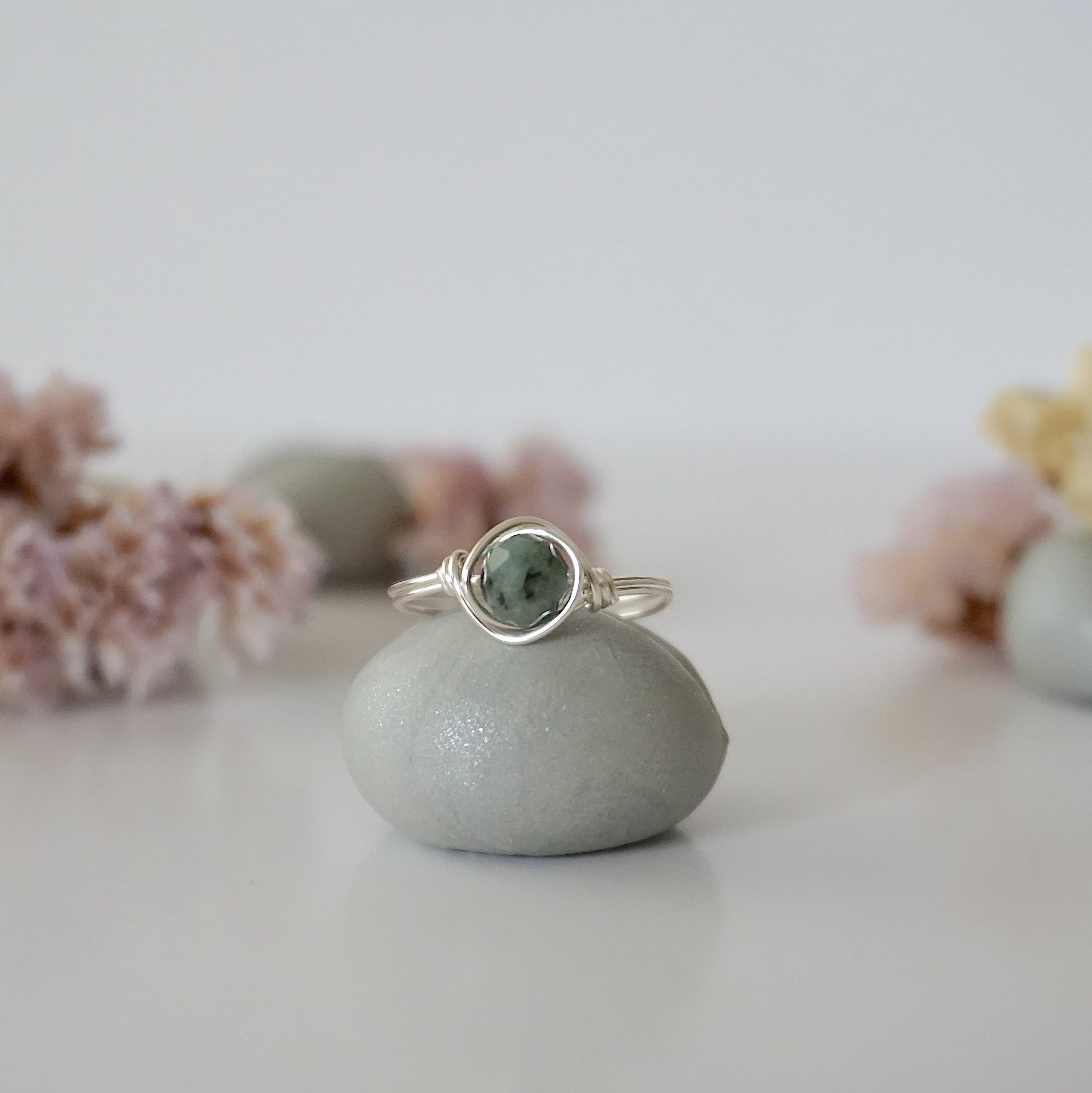 Front view of minimalist silver emerald ring with natural faceted emerald bead and artisan wire wrapping.