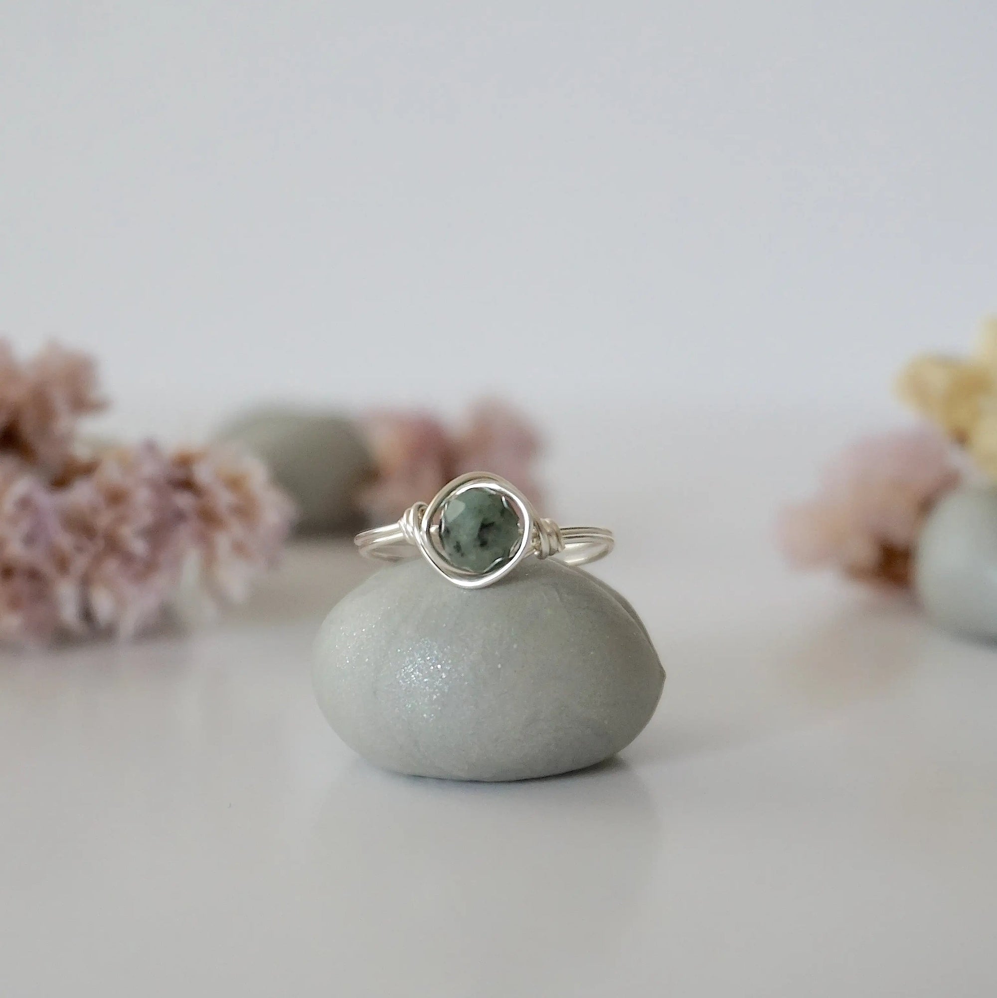 Front view of minimalist silver emerald ring with natural faceted emerald bead and artisan wire wrapping.