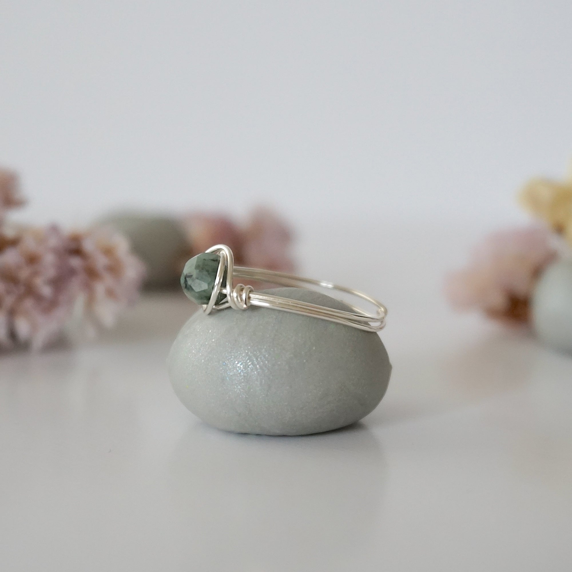 Side view of minimalist silver emerald ring showing classic artisan wire wrapping around a natural emerald bead.
