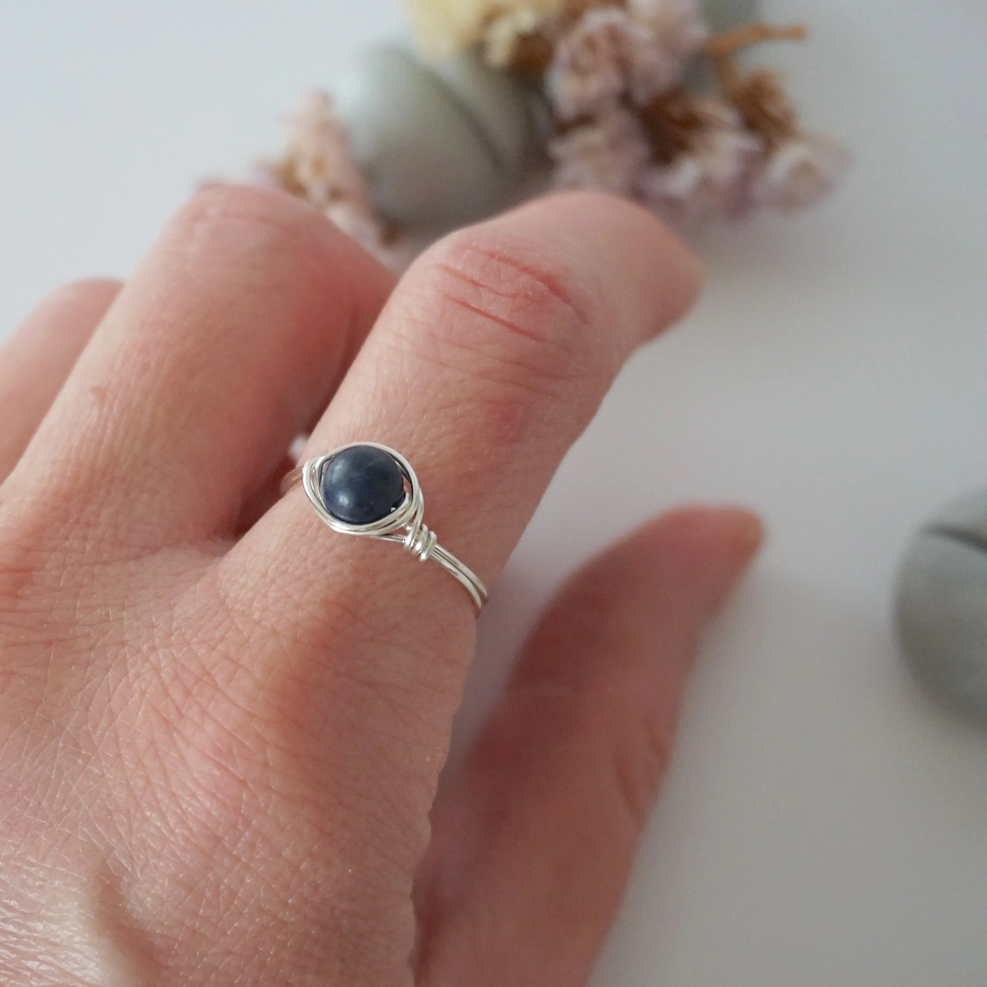 Woman wearing a minimalist silver wire-wrapped sapphire ring — natural September birthstone jewelry handcrafted by Designs by Nature Gems