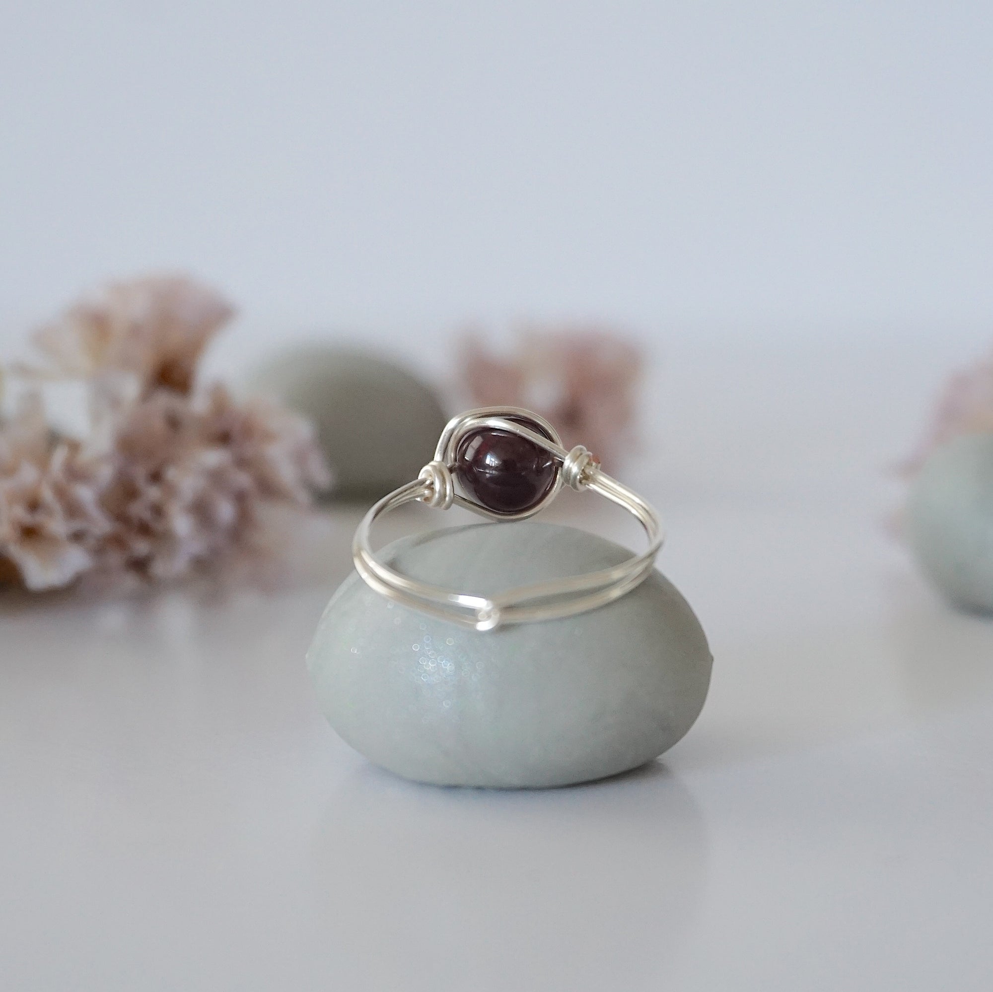 Back view of minimalist silver wire wrapped garnet ring band, dainty January birthstone jewelry