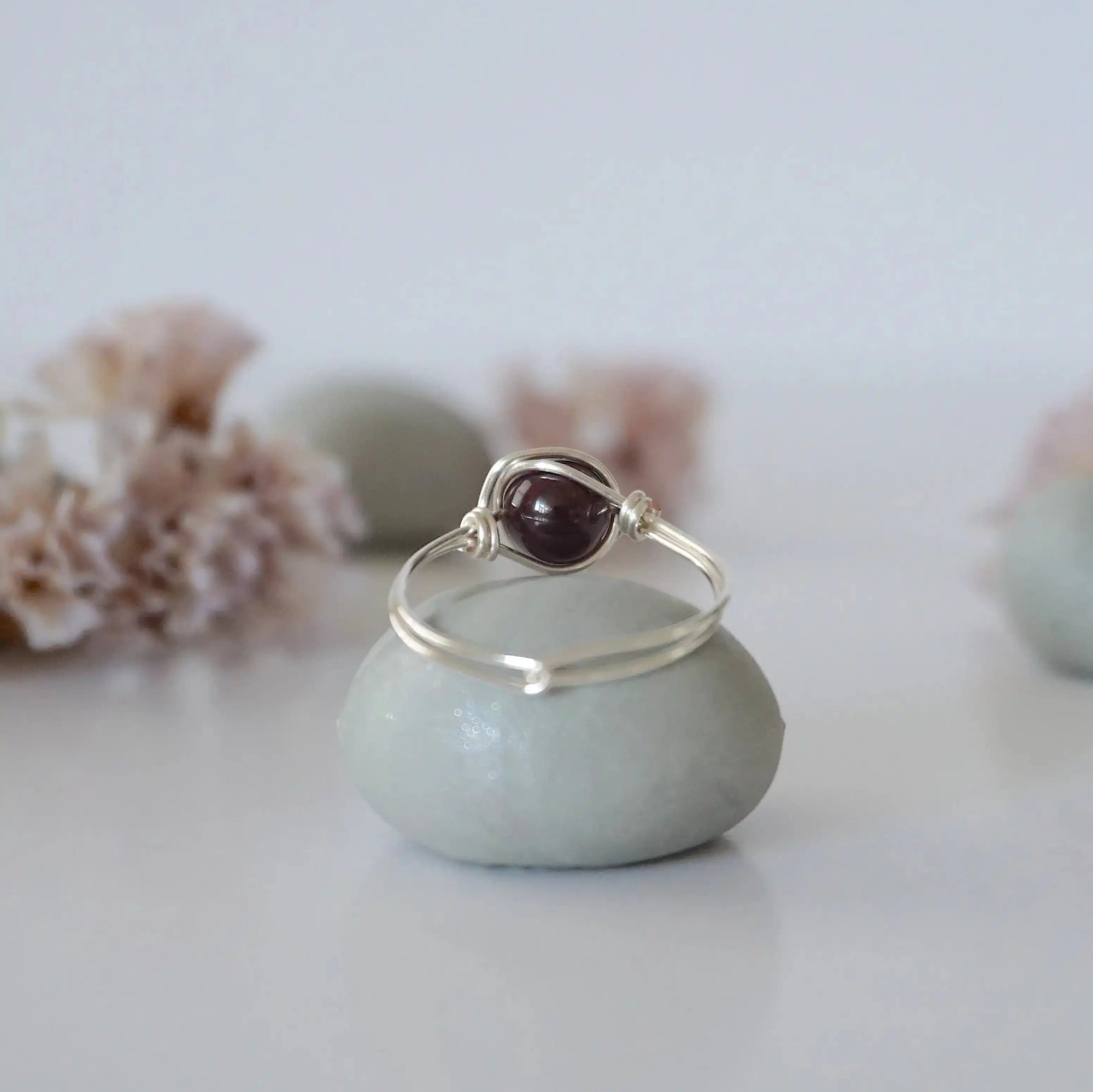 Back view of minimalist silver wire wrapped garnet ring band, dainty January birthstone jewelry