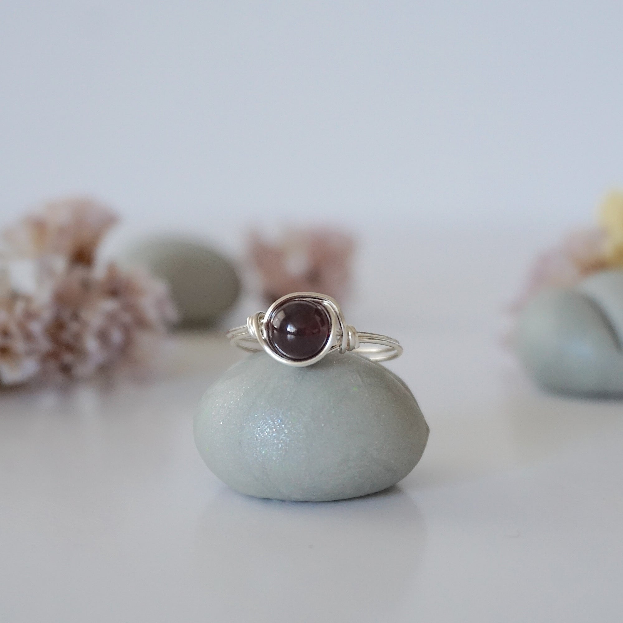 Front detail of minimalist silver wire wrapped garnet ring featuring a single polished garnet bead
