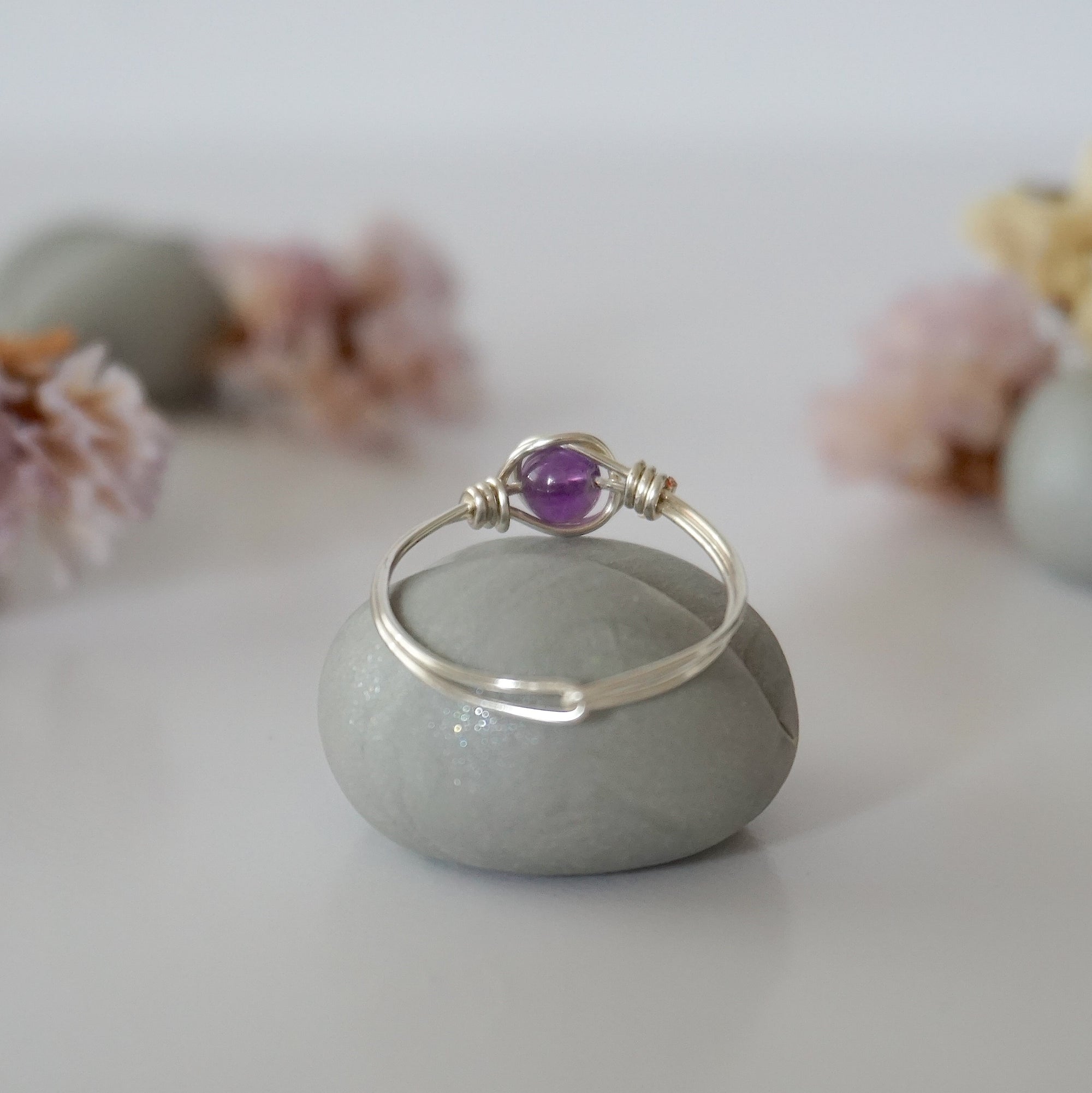 Back view of silver amethyst ring showing minimalist wire wrapped band and polished 6mm amethyst bead setting