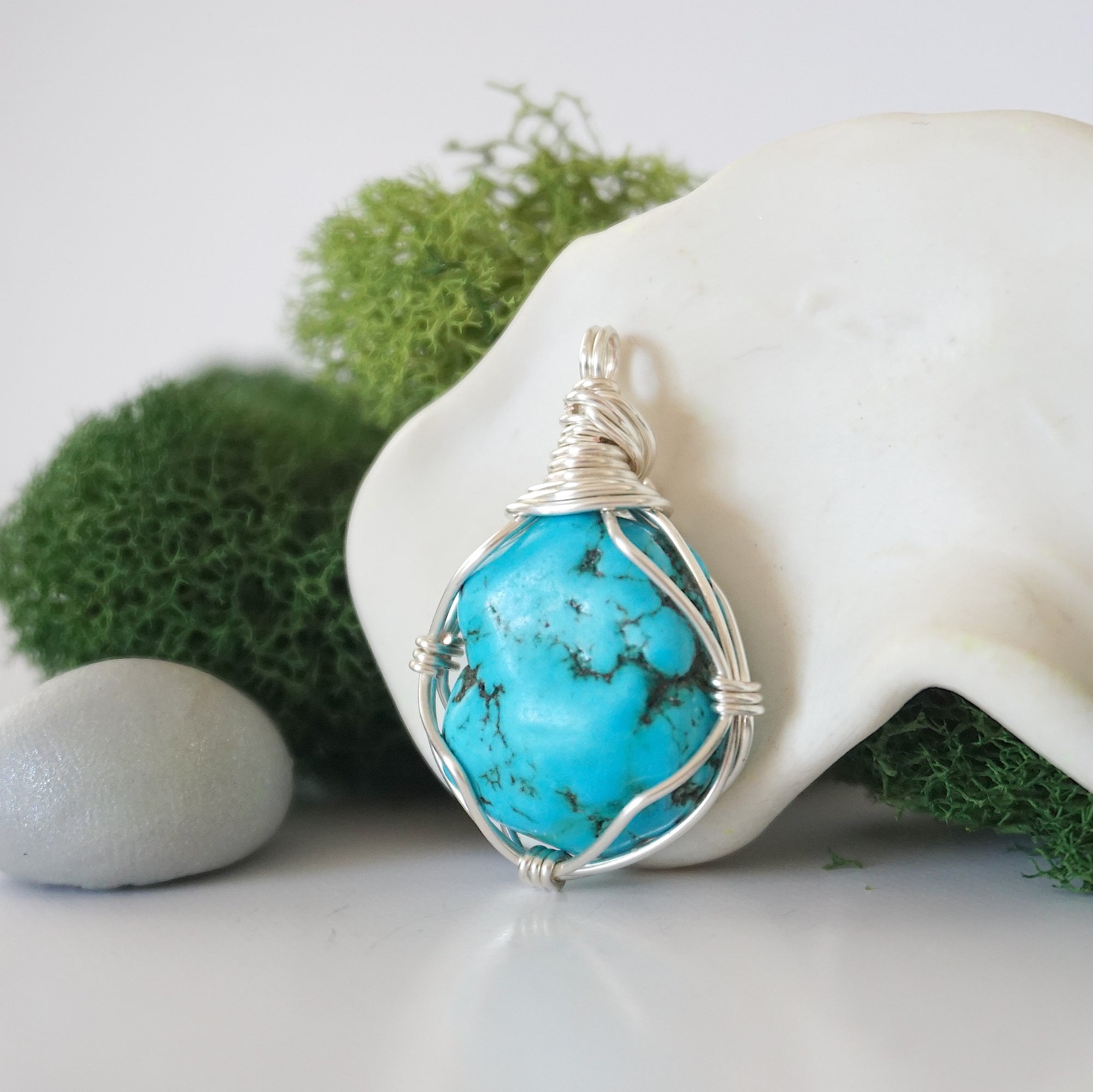Side angle of simple raw turquoise pendant showing minimalist wire wrap technique with silver plated copper wire