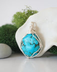 Side angle of simple raw turquoise pendant showing minimalist wire wrap technique with silver plated copper wire
