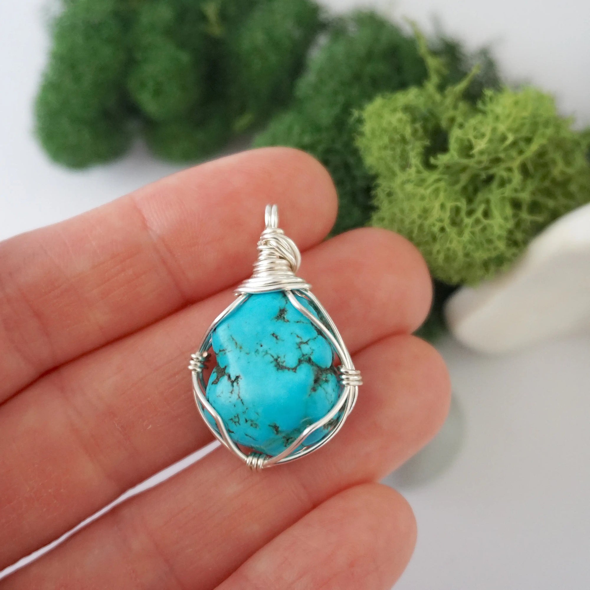 Simple raw turquoise pendant in hand showing size, minimalist wire wrapped crystal necklace scale reference
