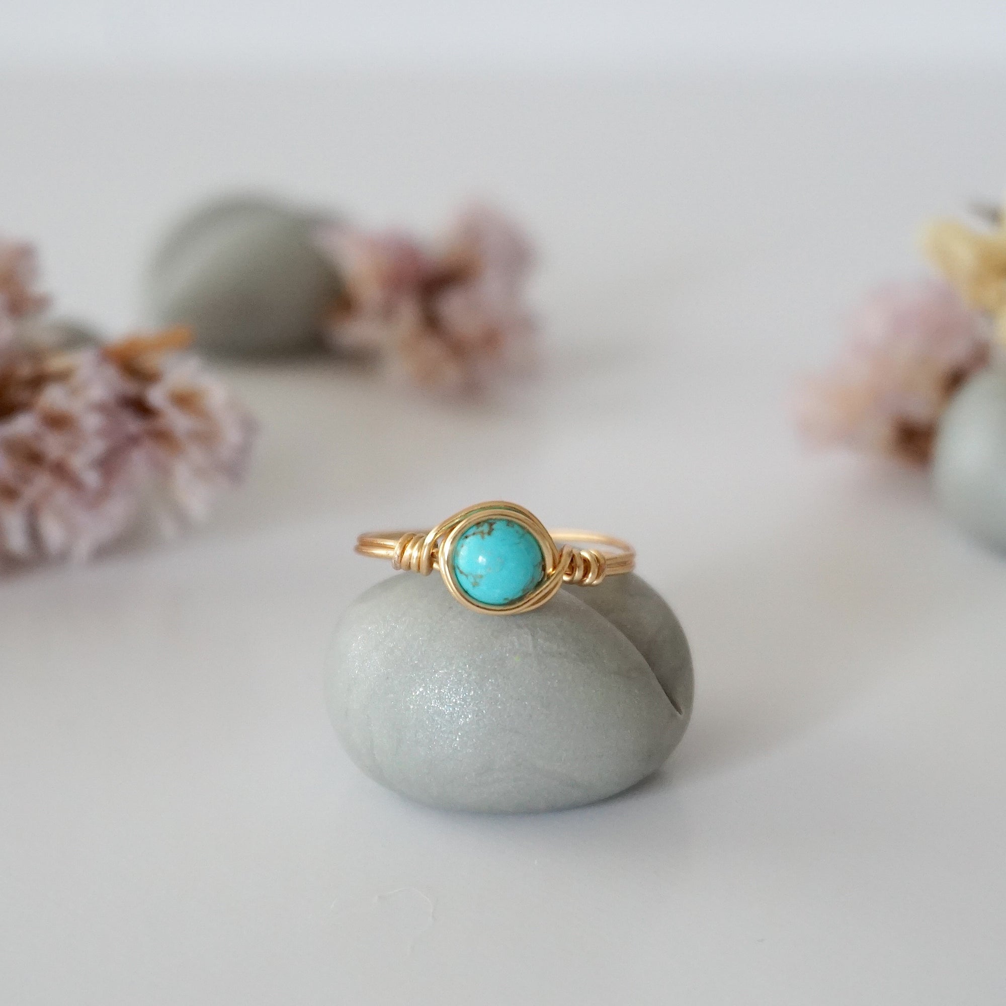 Front view of simple turquoise ring in gold plated copper showing 6mm polished stone and handmade wire wrapping detail