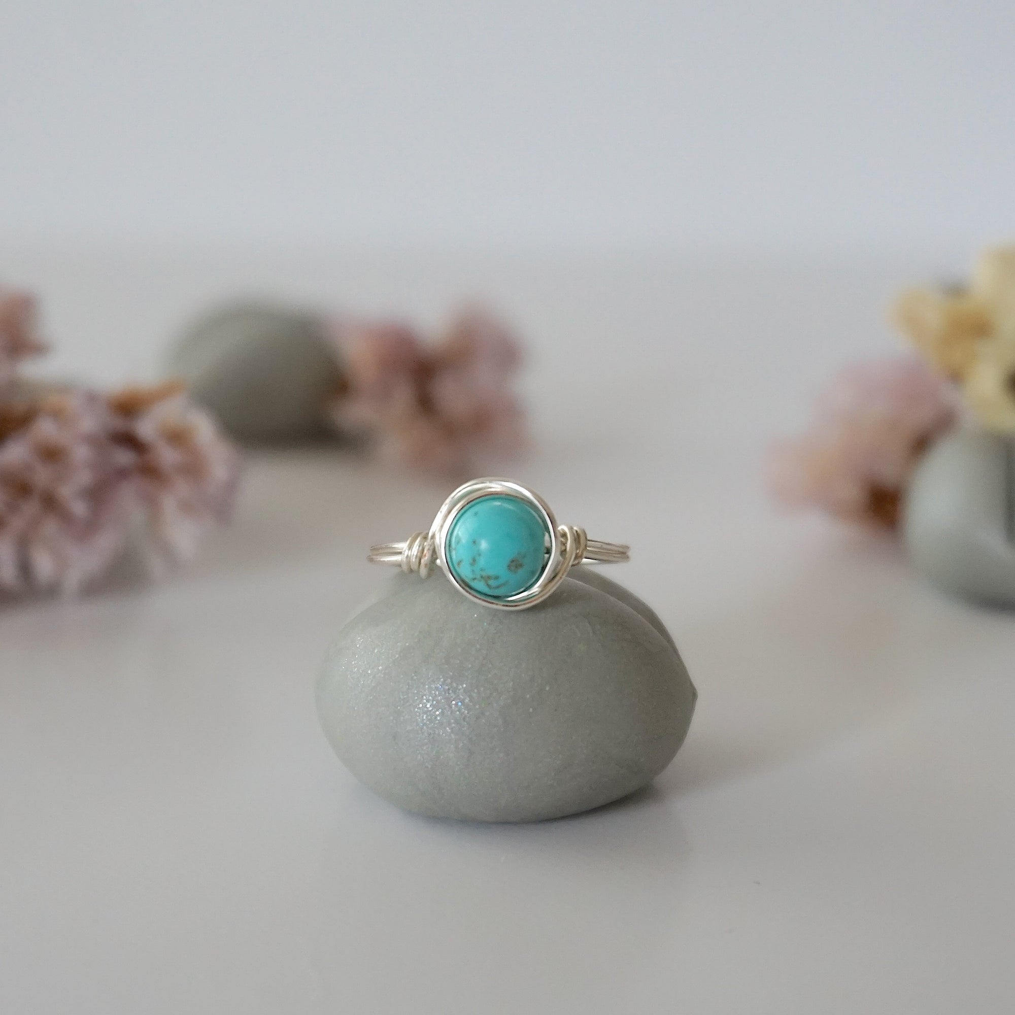Front view of simple turquoise ring in silver plated copper showing 6mm polished stone and handmade wire wrapping detail