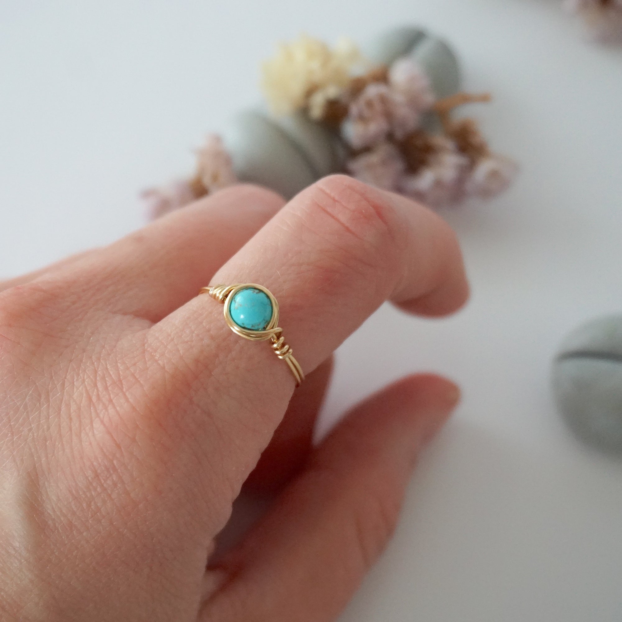 Simple turquoise ring for women in gold plated copper worn on hand showing 6mm polished stone and minimalist wire wrap