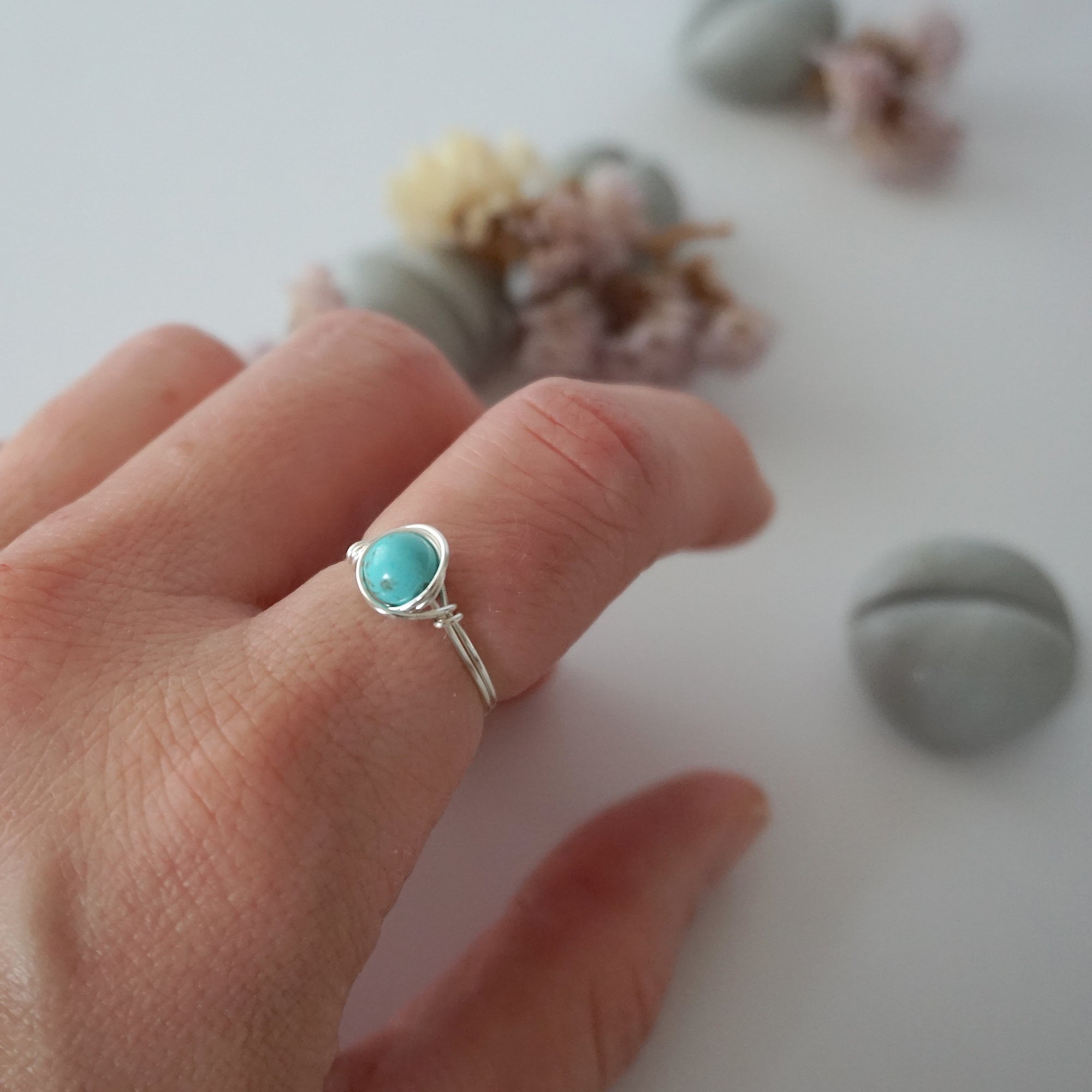 Simple turquoise ring for women in silver plated copper worn on hand showing 6mm polished stone and minimalist wire wrap