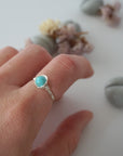 Simple turquoise ring for women in silver plated copper worn on hand showing 6mm polished stone and minimalist wire wrap