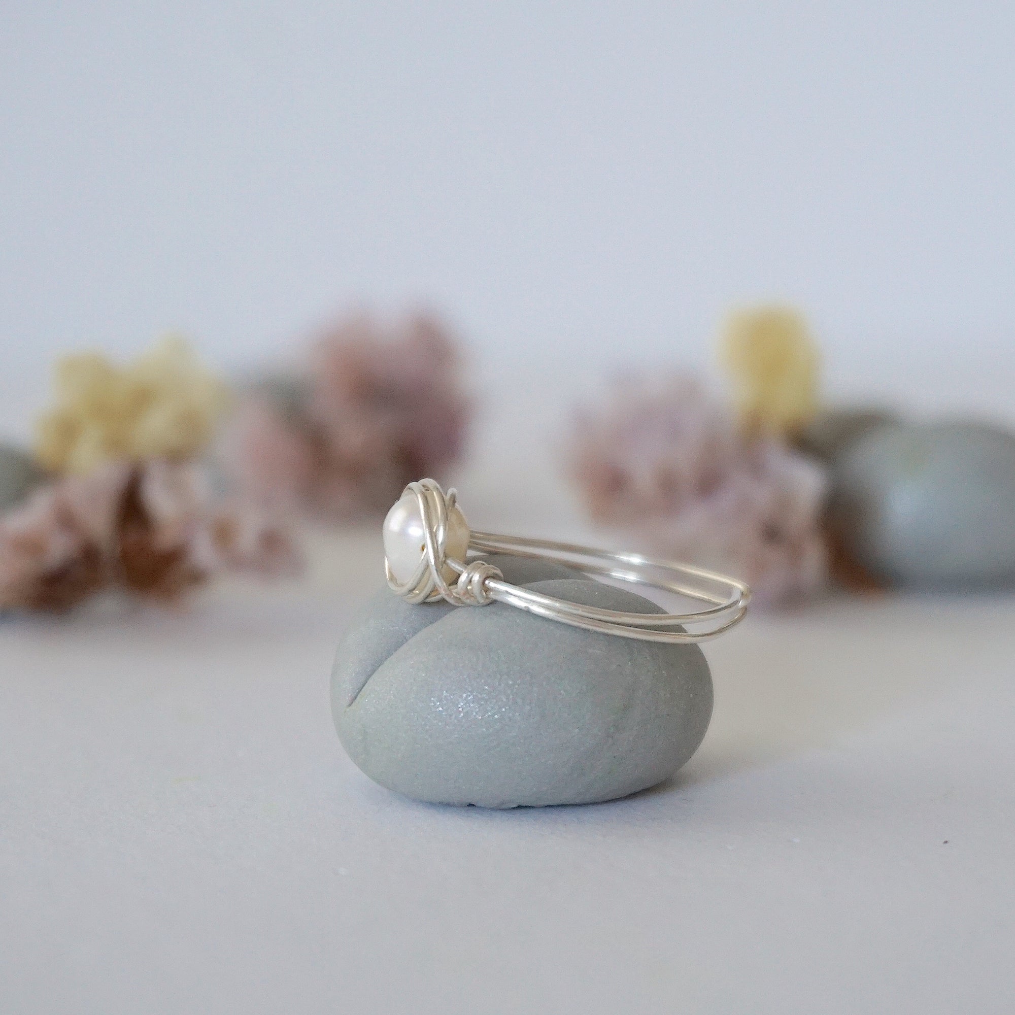 Side view of a sterling silver pearl wire wrapped ring showing minimalist craftsmanship
