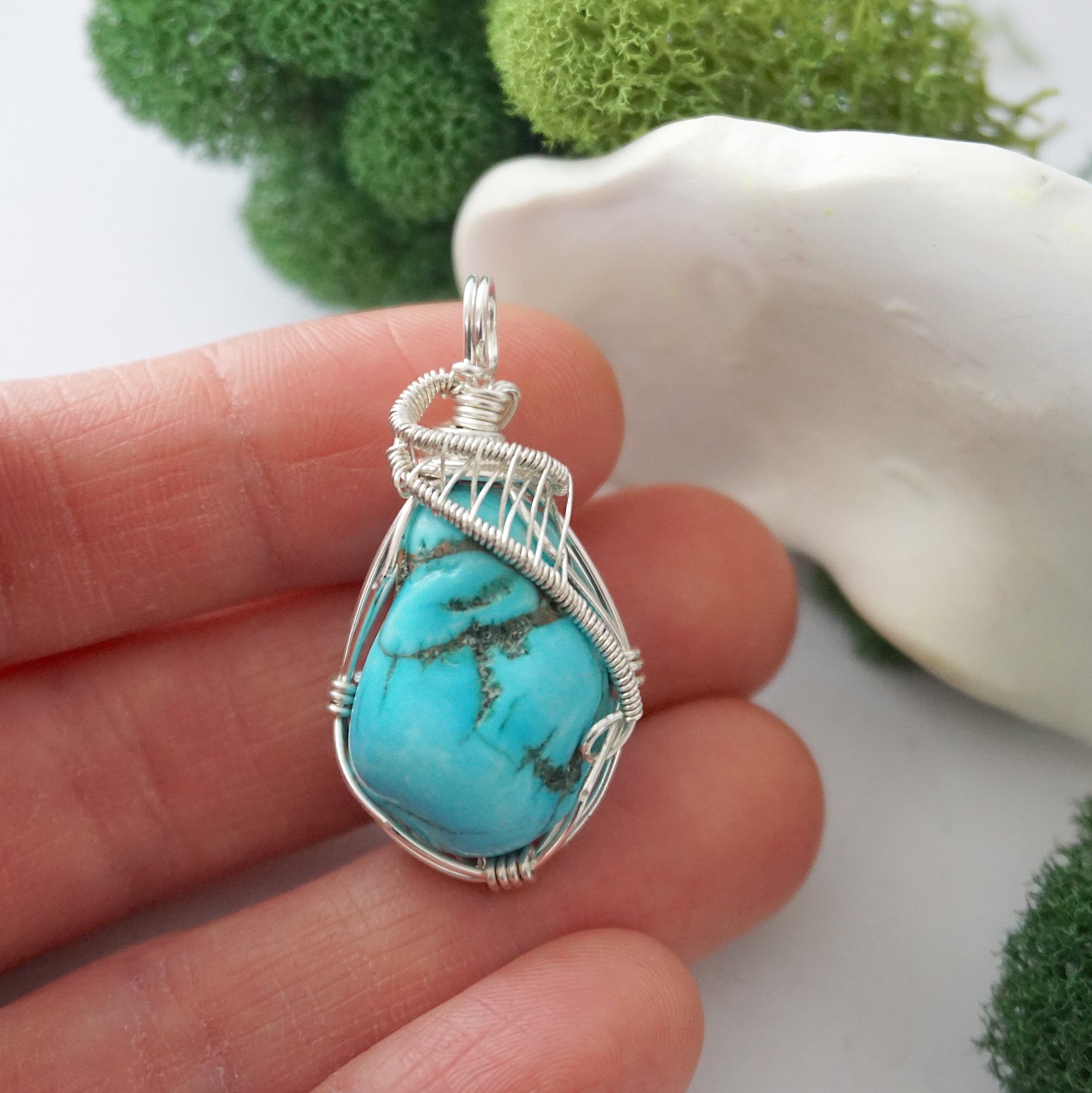 Raw turquoise pendant in hand showing size, sterling silver wire wrapped crystal necklace for women scale reference