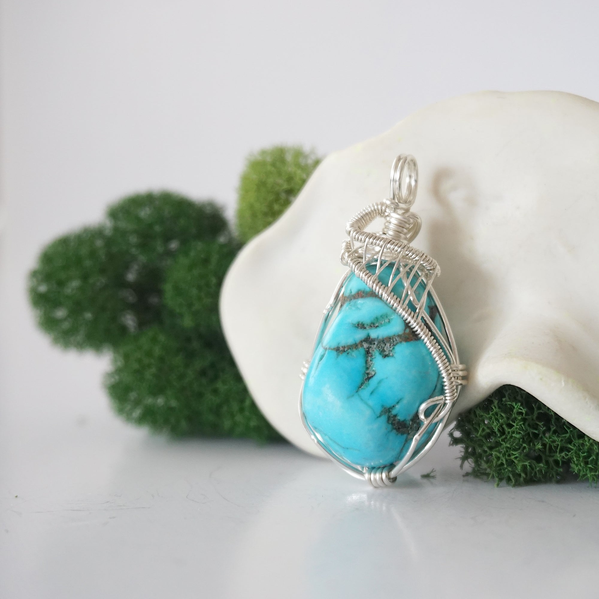 Side angle of sterling silver raw turquoise pendant showing intricate wire wrap detail and natural crystal texture