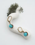 Bird’s eye view of turquoise drop earrings laying flat on a display, showing detailed wire wrapping and gemstone color.