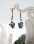 Close-up of handcrafted turquoise drop earrings with antique bronze copper wire wrapping.