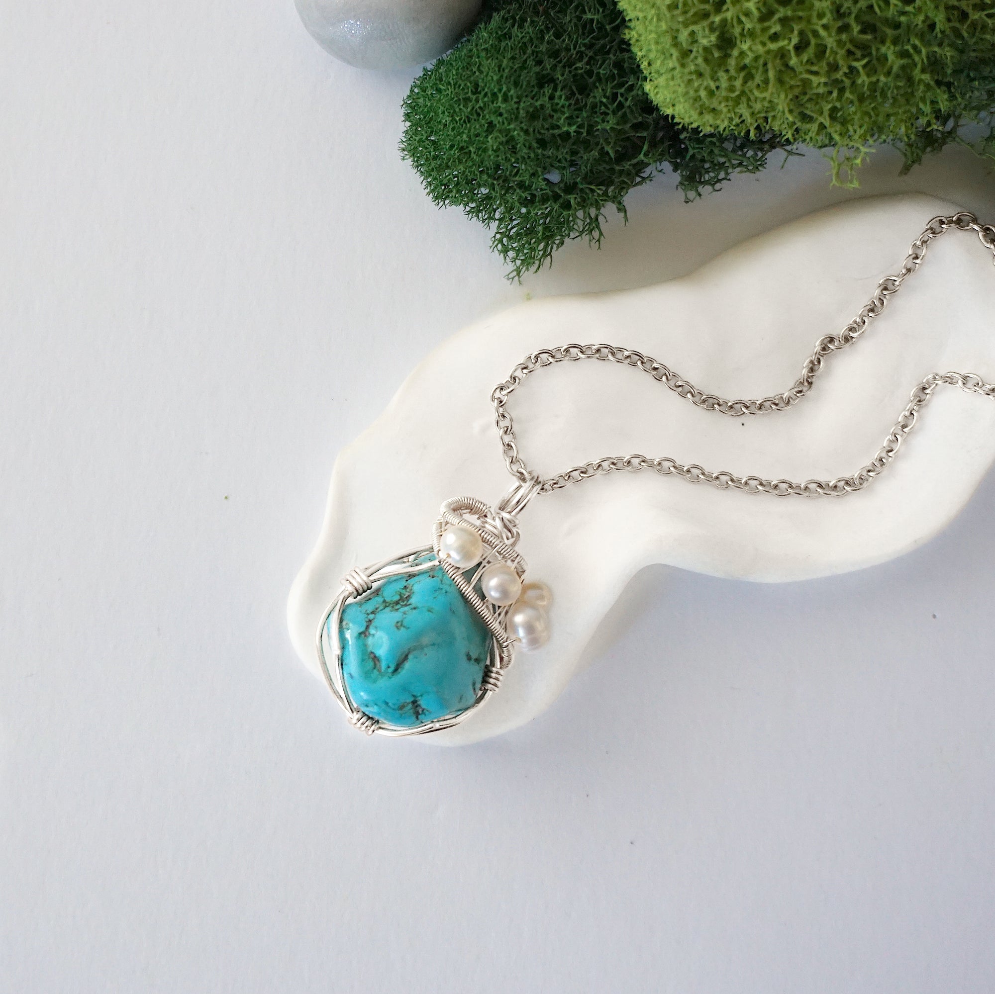 Handmade silver wire wrapped turquoise and freshwater pearl necklace laying flat on a silver plated chain, artisan jewelry for women