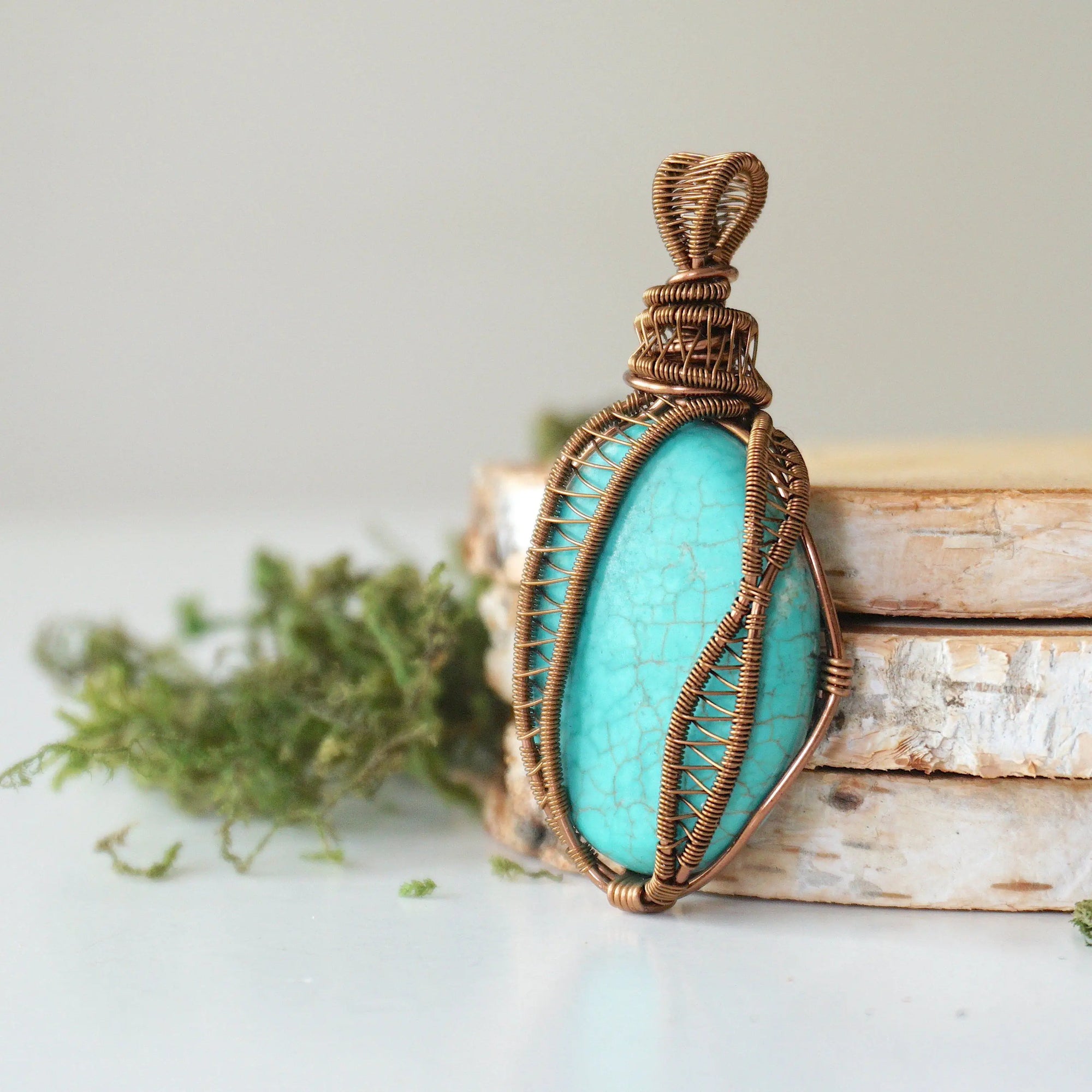 Side profile of handmade turquoise pendant showing detailed wire wrapping technique and natural stone depth in antique bronze
