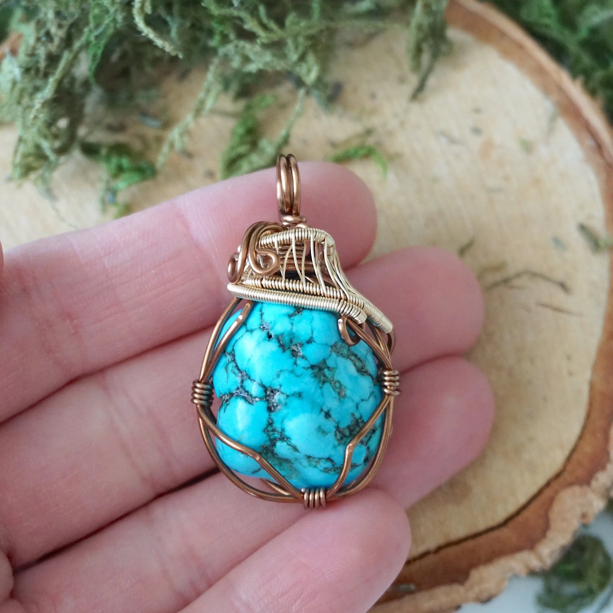 Mixed metal turquoise pendant size in hand showing bronze gold wire detail