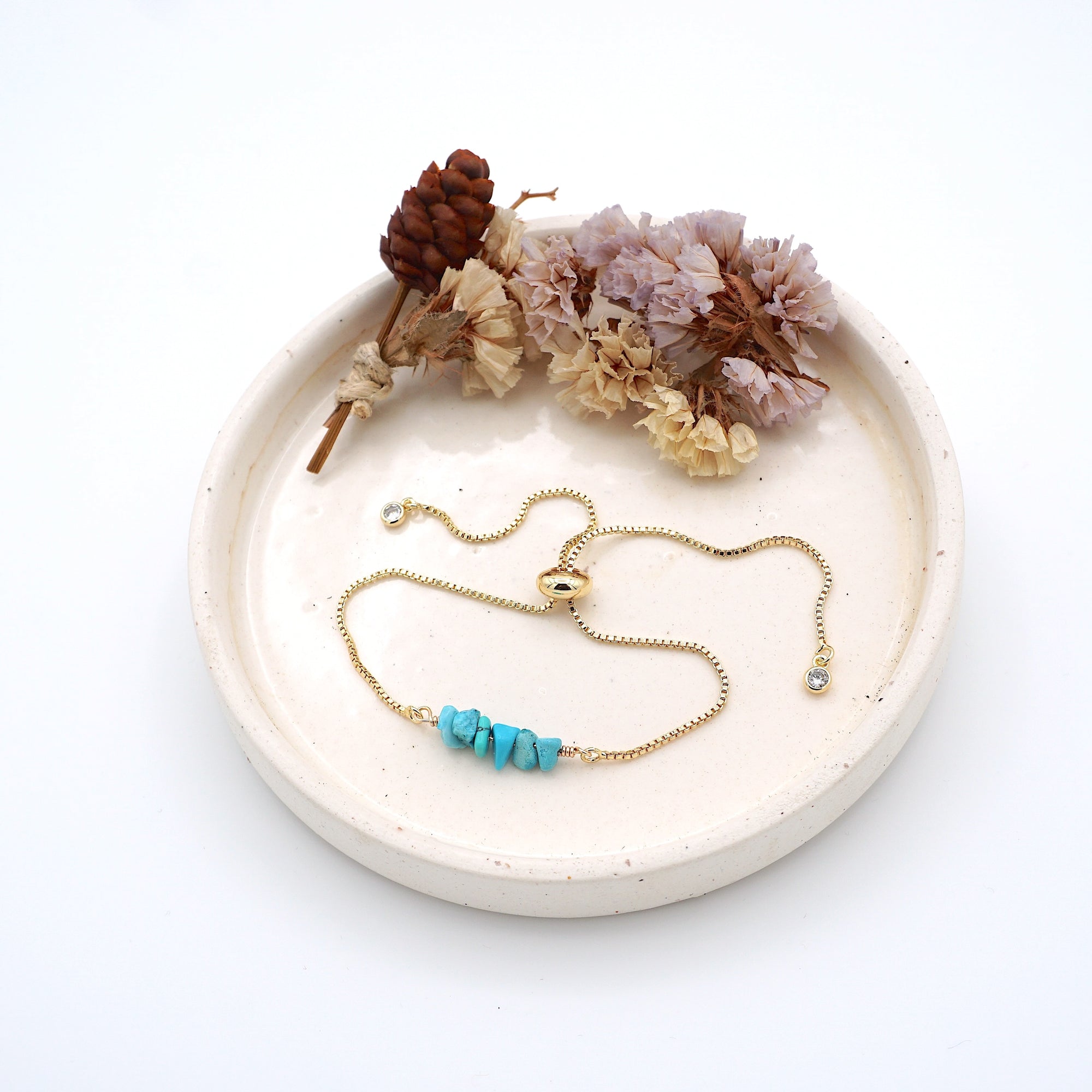 Handmade turquoise bracelet displayed on ceramic tray showing natural blue-green crystals and gold chain - December birthstone gift for her