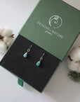 Turquoise sterling silver drop earrings in branded Designs by Nature Gems jewelry box, showcasing handcrafted faceted turquoise and sterling silver wire wrapping