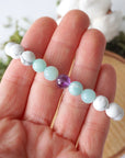 Bracelet in hand showing detailed view of white howlite, amethyst, and amazonite beads, natural crystal stretch bracelet